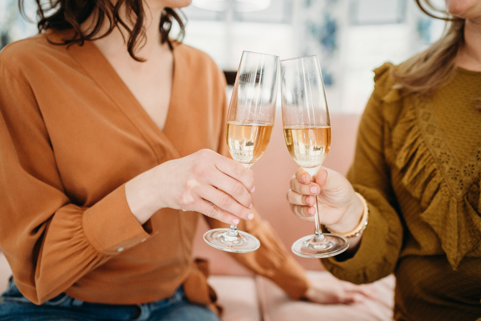 two women clink champagne glasses together