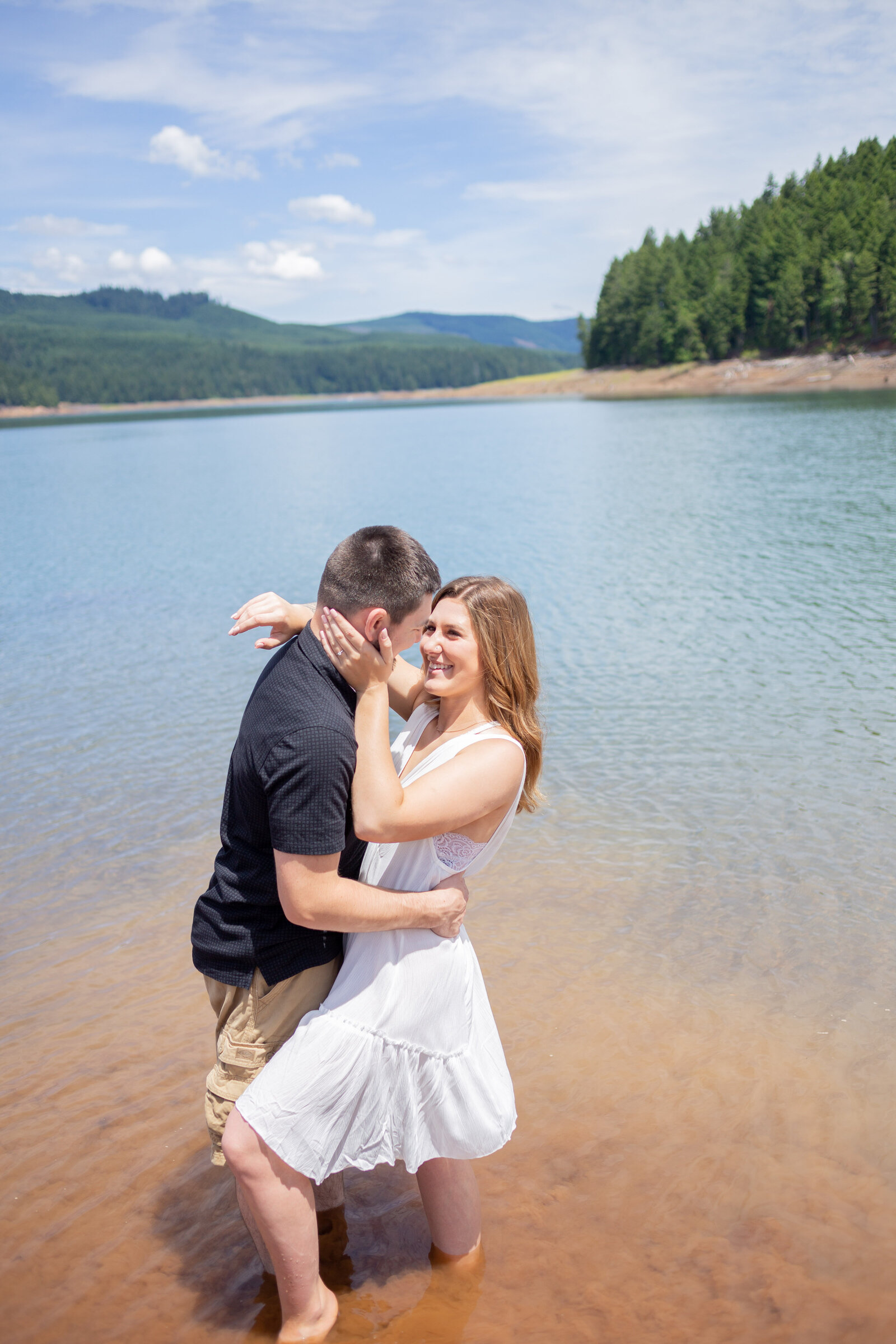 Seattle Wedding Photographer captures photo in lake with couple looking at each other and mountains in the background