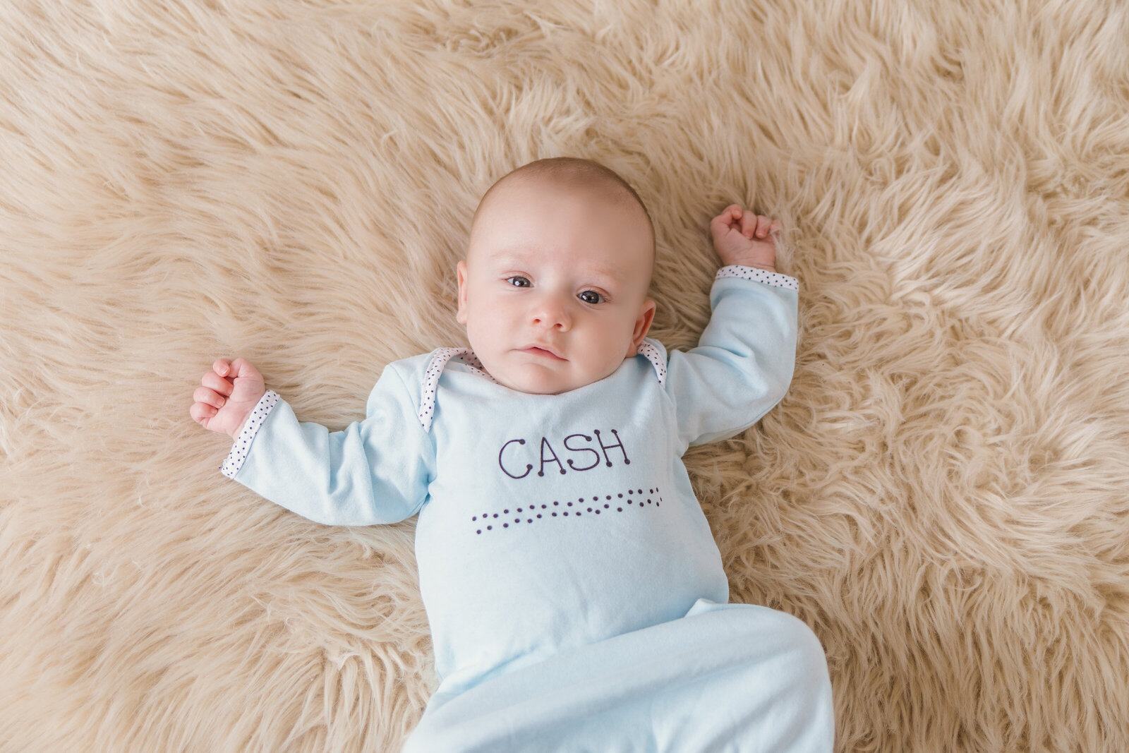 Milestone Photographer,  a baby lays on shag carpet