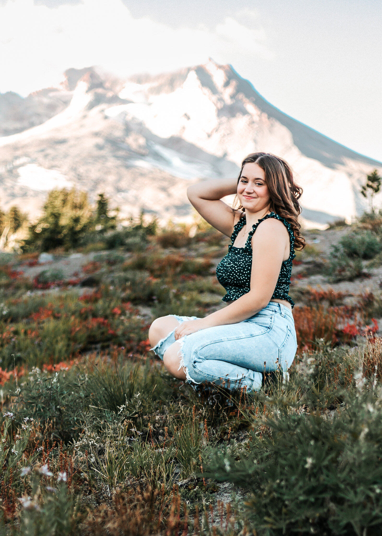 Girl sitting with a gorgeous view of Mount Hood behind her up at Timberline Lodge
