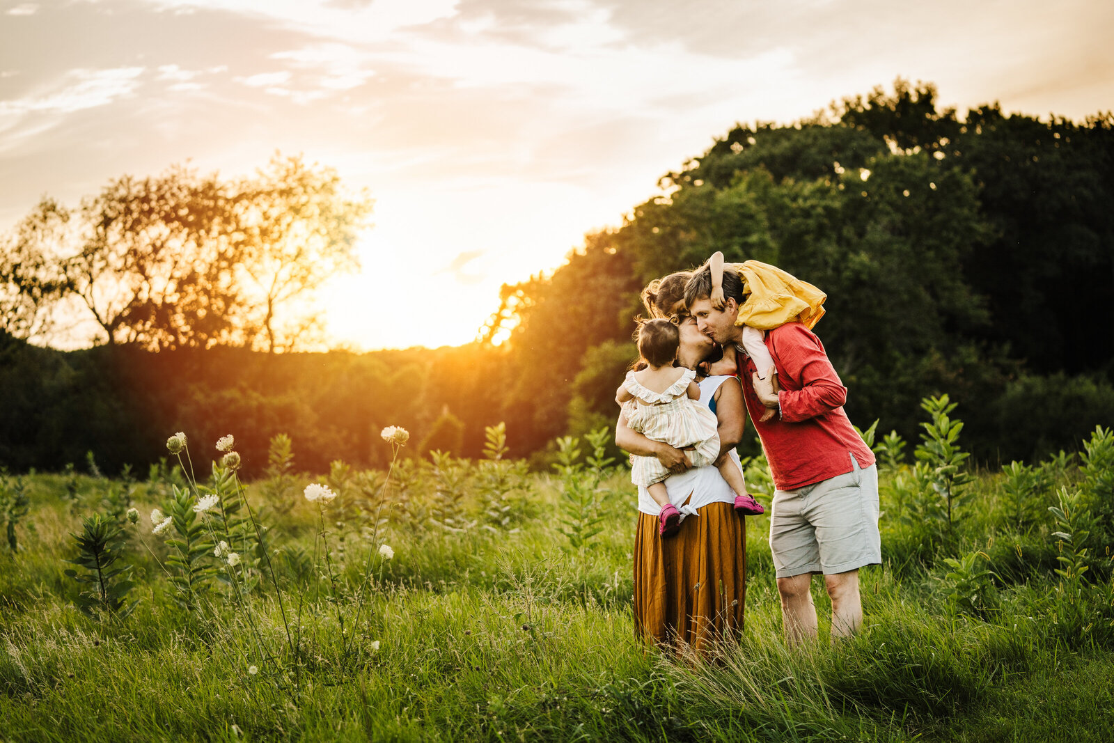 family hug in a field at sunset