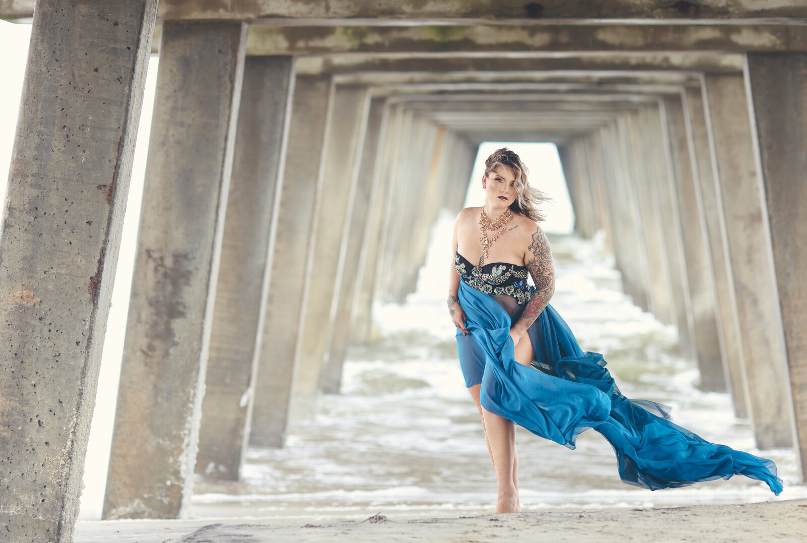 Woman in blue flowy gown under bridge