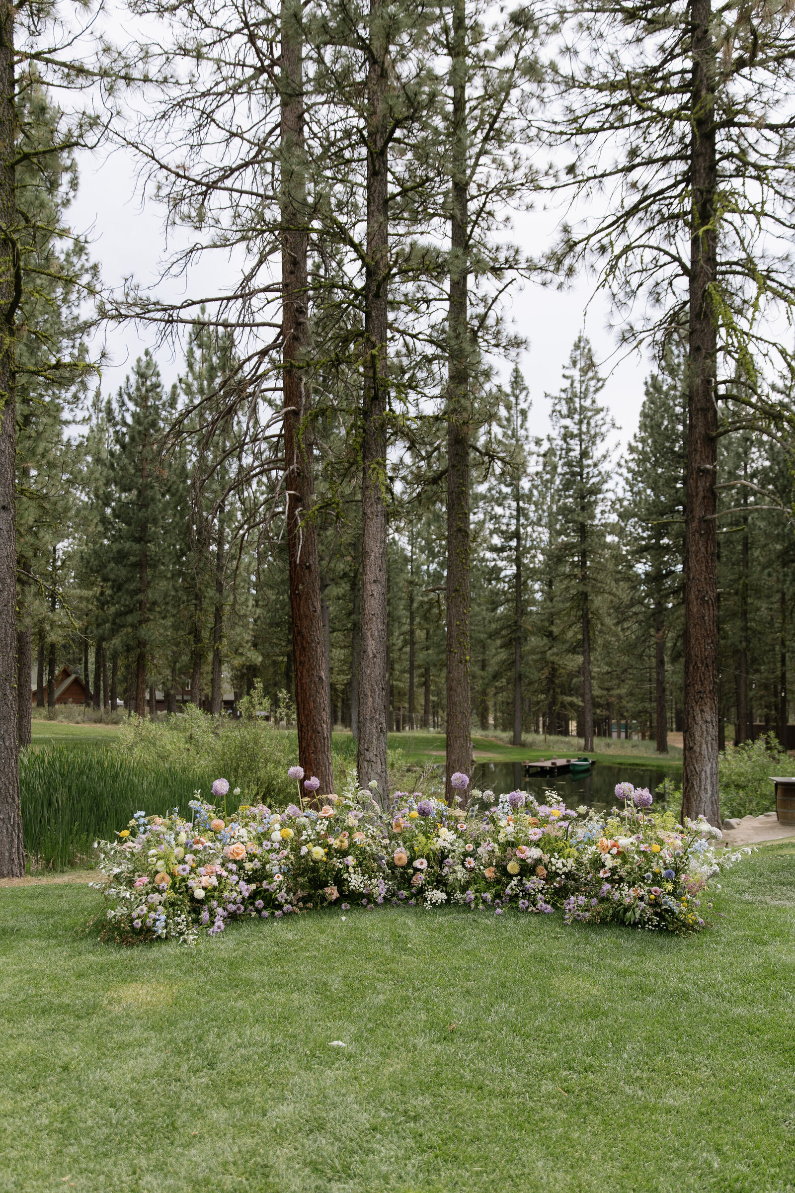 Colorful retro-inspired floral arch for Lake Tahoe forest wedding ceremony