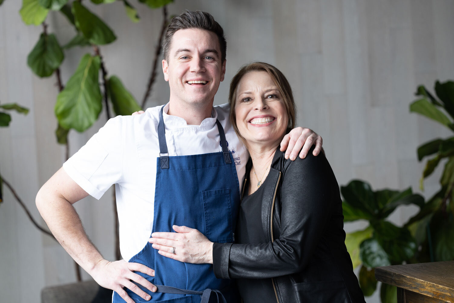 A man in an apron stands next to a woman in a black jacket