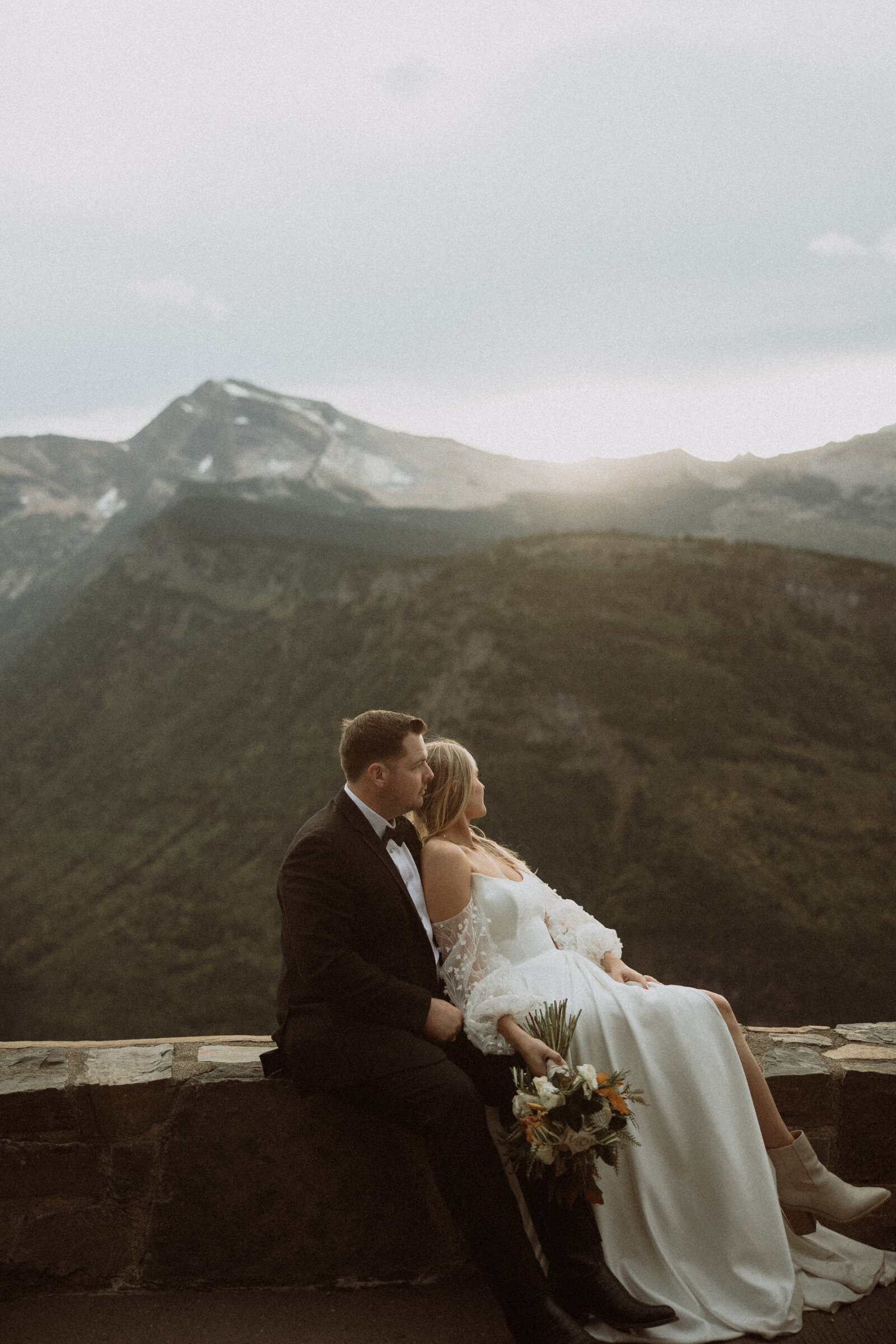 bride and groom sitting on ledge at a montana elopement day