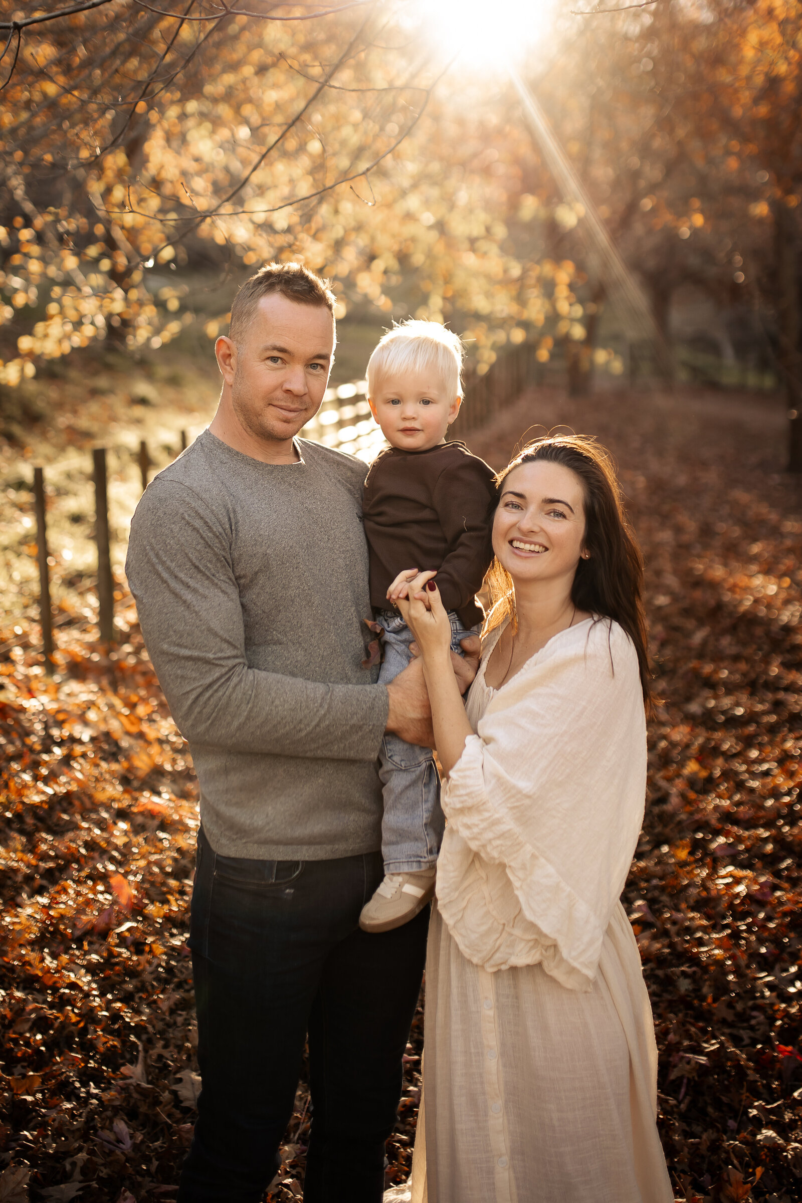 Family of four playing in a blanket of vibrant autumn leaves at Dolbel Reserve, Taradale, Hawke’s Bay – candid family photography capturing joyful moments amidst the golden hues of native bush, ideal for maternity, newborn, and family sessions in Napier and Hastings