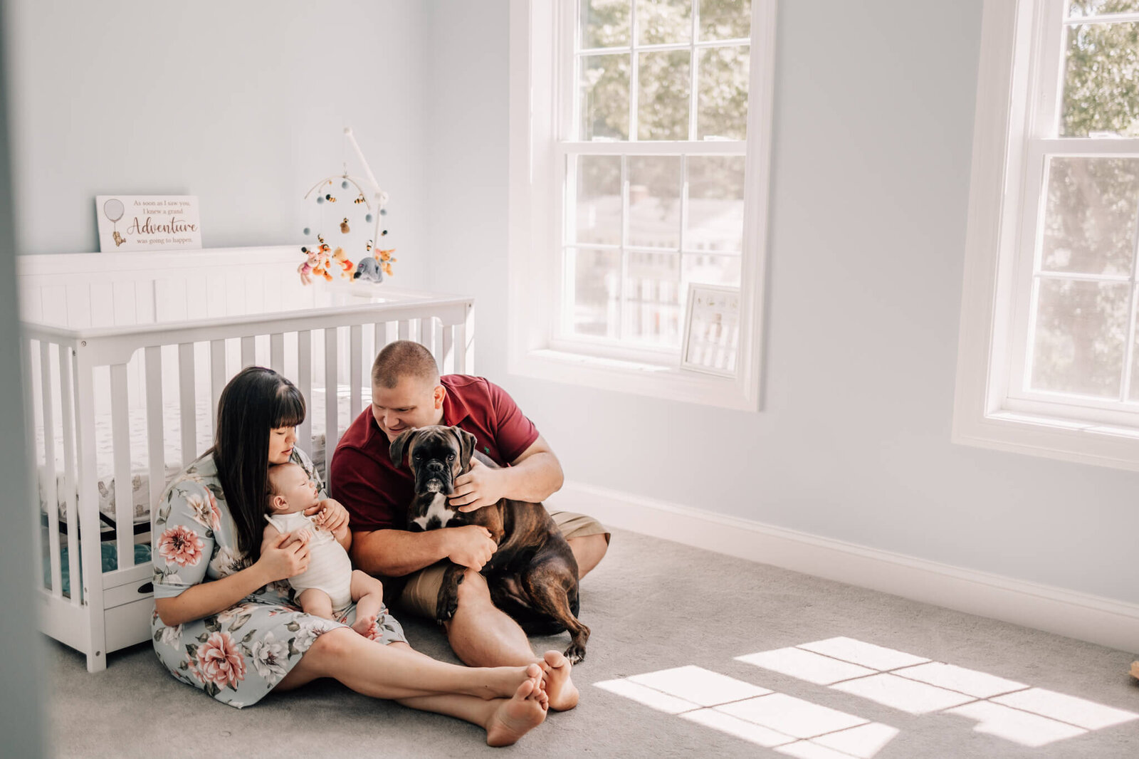 Mom, Dad, Baby, and dog in nursery sitting in front of crib
