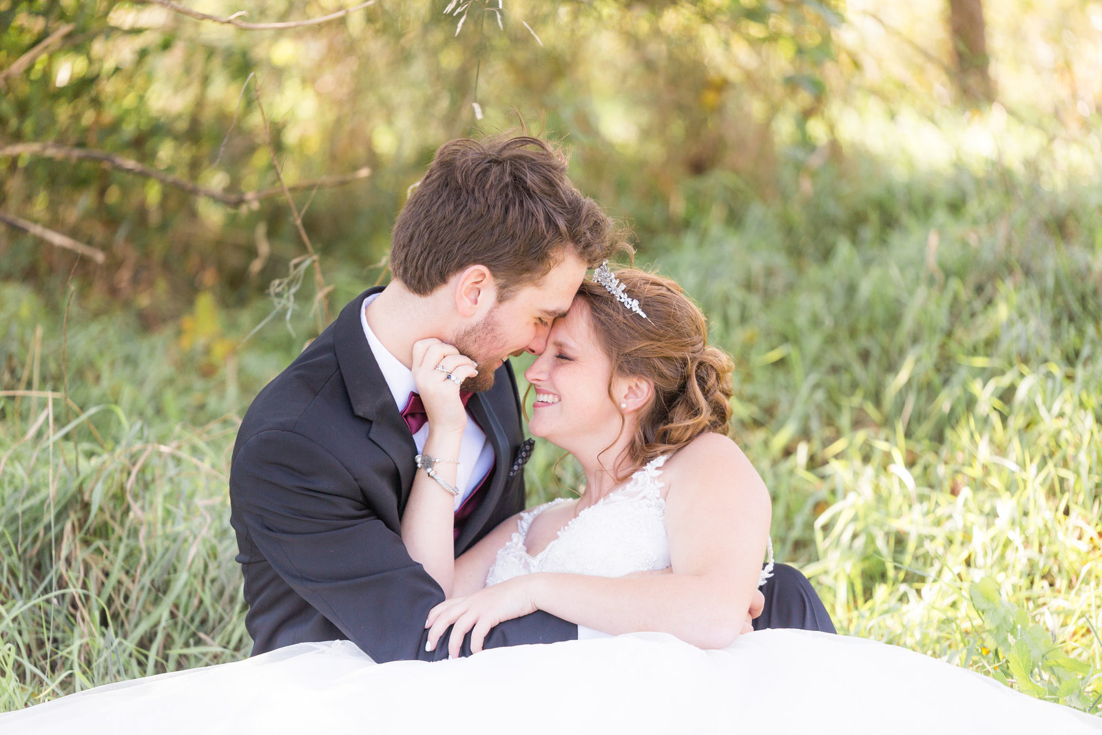 bride and groom sit in grass