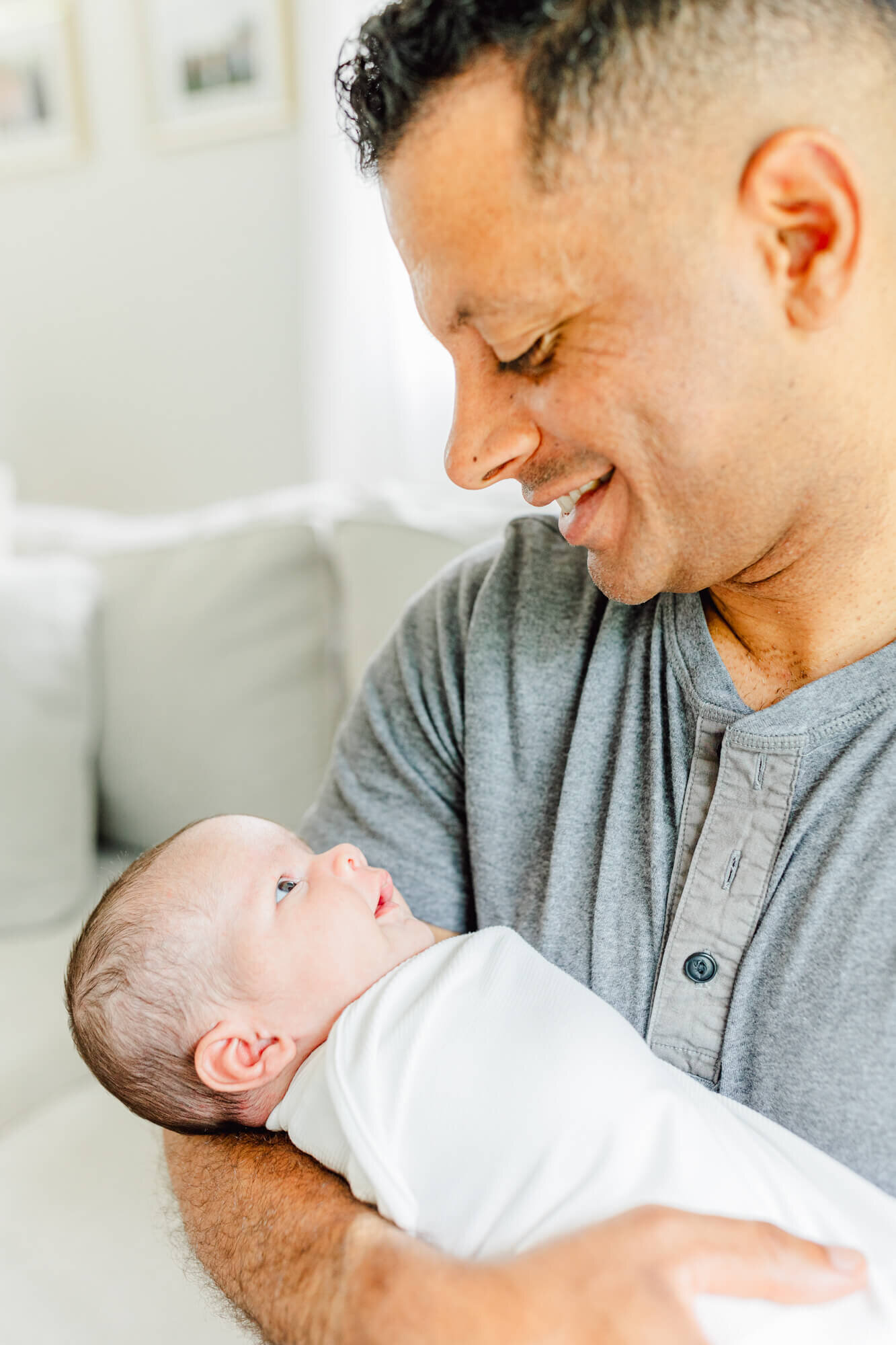 Swaddled newborn and dad smile at each other