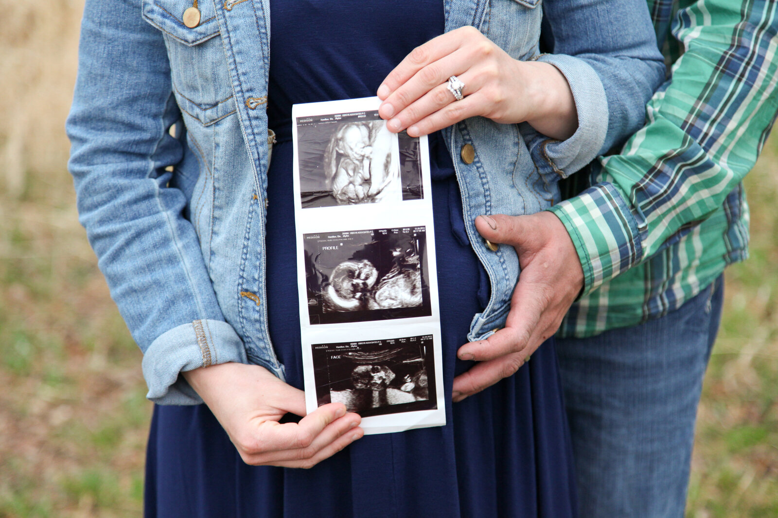 Close up of pregnant belly with sonogram in front of it.