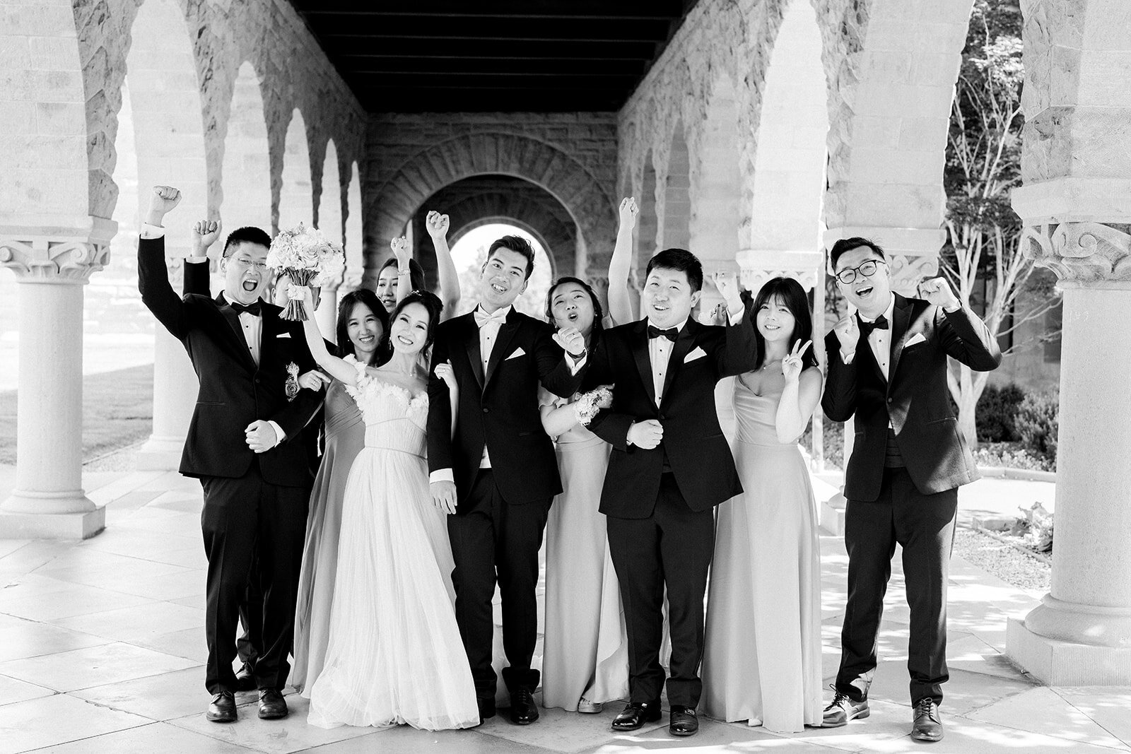 The bridal party shares a moment of joy and celebration amidst the scenic beauty of Stanford University.