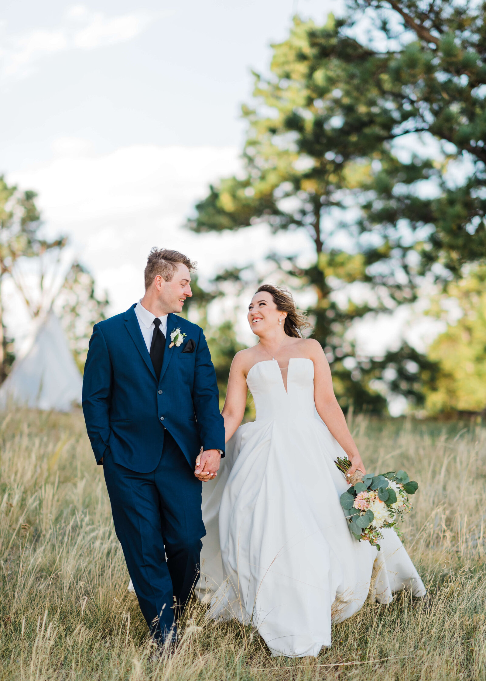 Handsome groom and beautiful bride walk together in a field in an image taken by Virginia wedding photographer