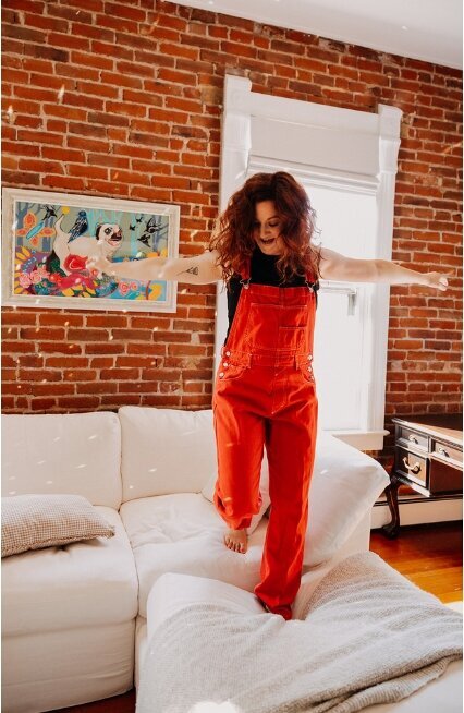 A woman jumping on a couch.