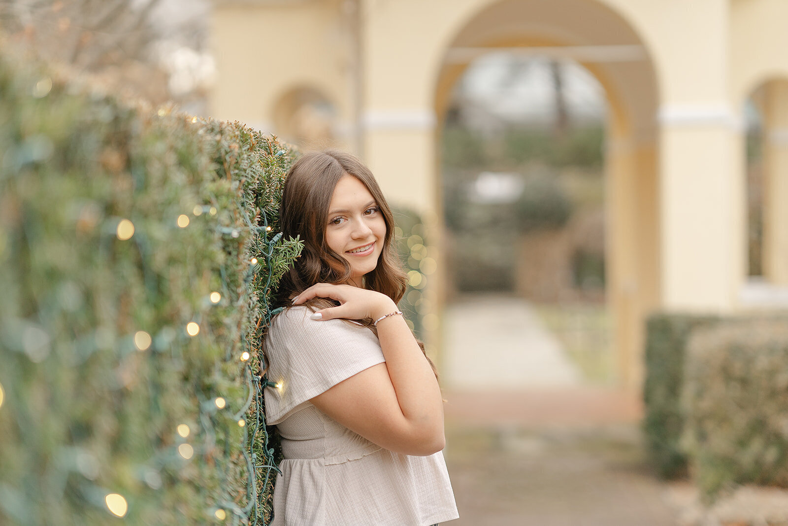 girl leaning on a shrub during Warrenton, Virginia senior picture