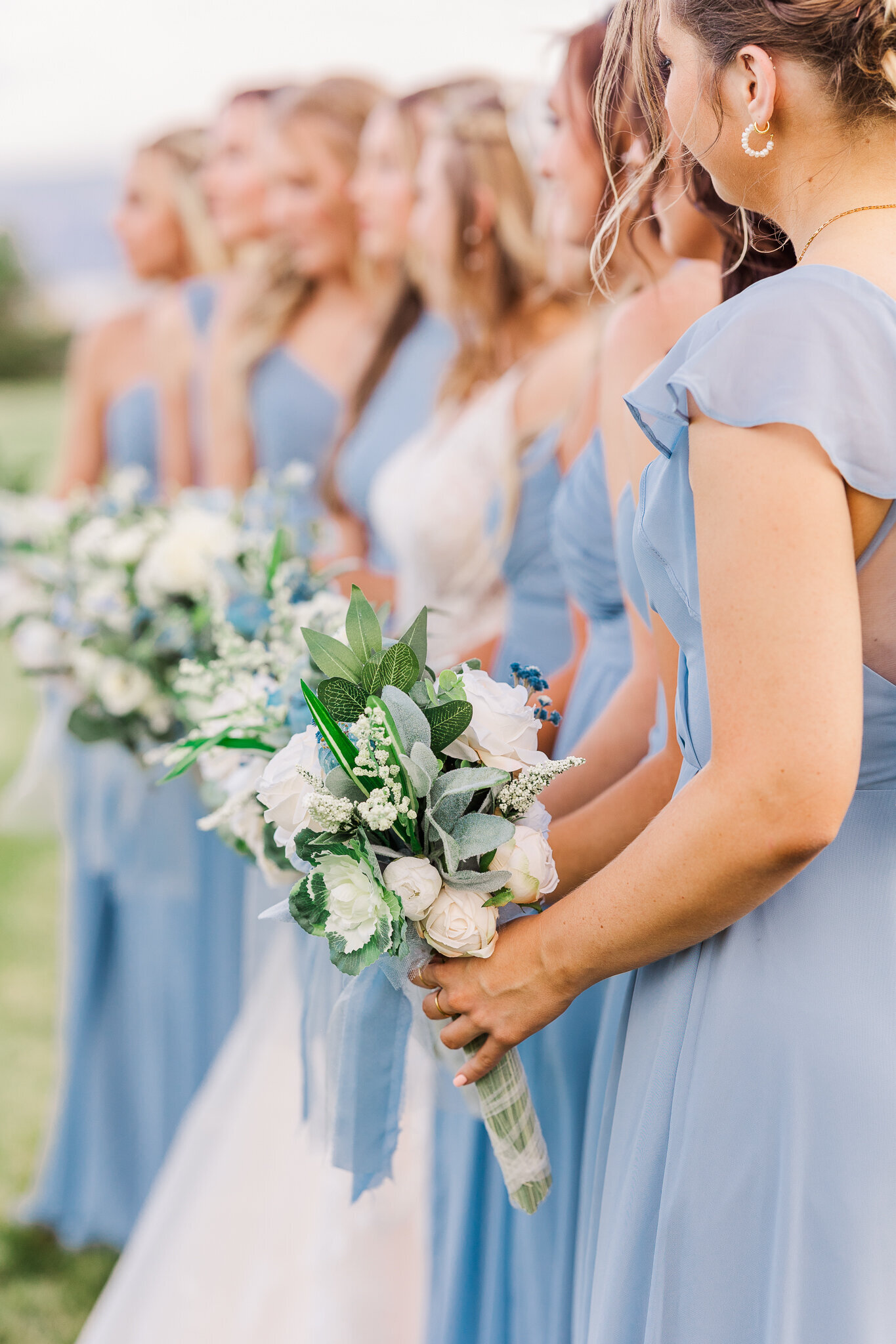 Vertical photo of bridesmaids holding matching blue and white bouquets at Absolute Prestige wedding venue in Loma, Colorado