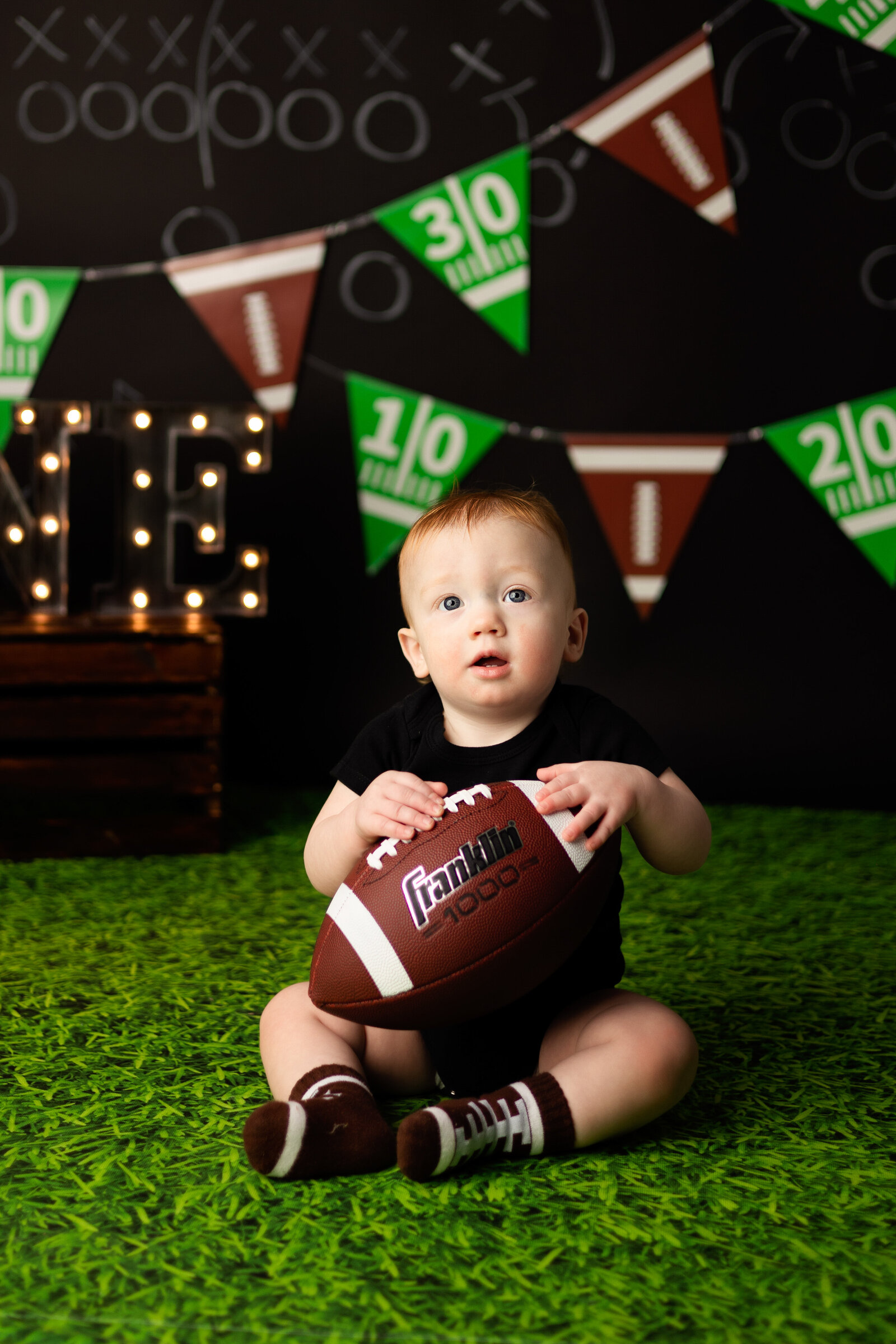 Adorable baby boy holding a foot ball, sits contently