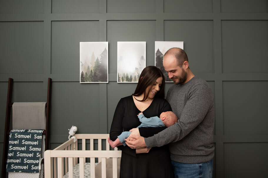 Macomb Township family with newborn posing in a forest green nursery