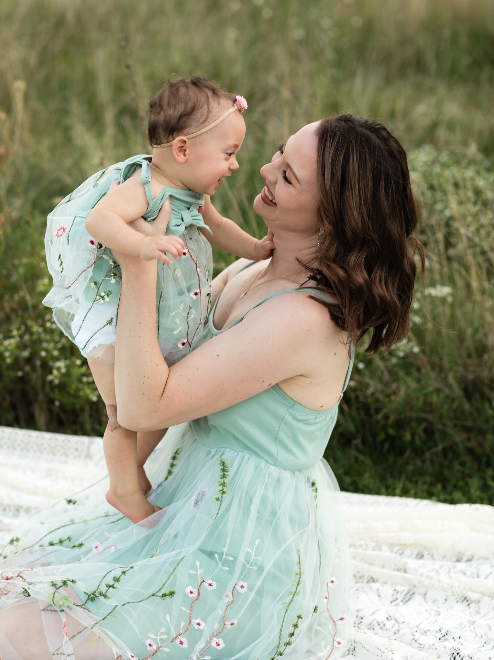 mom holding up daughter while sitting on the ground for family photos cleveland family photography