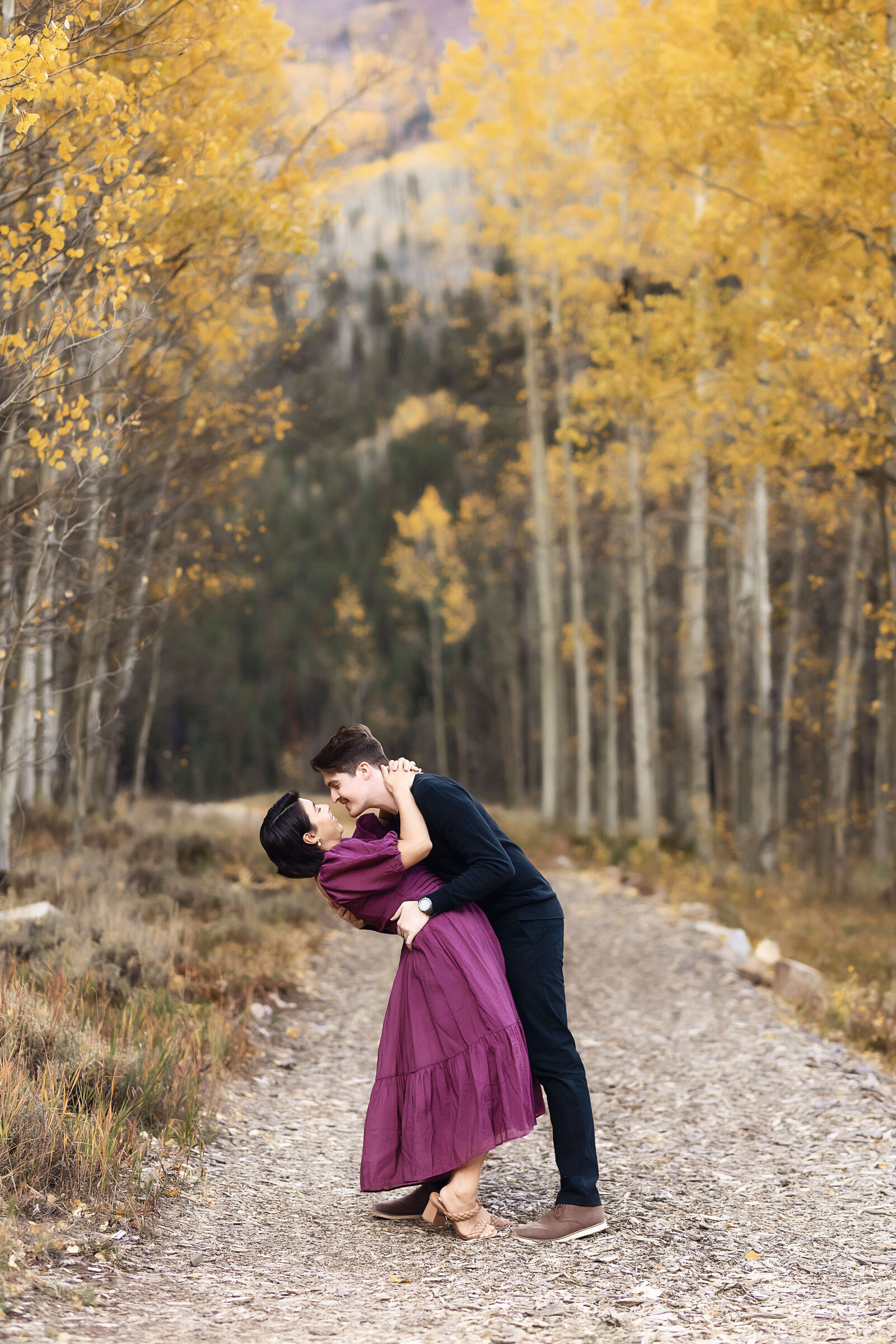 A man dips his fiance in a romantic aspen grove fall setting.