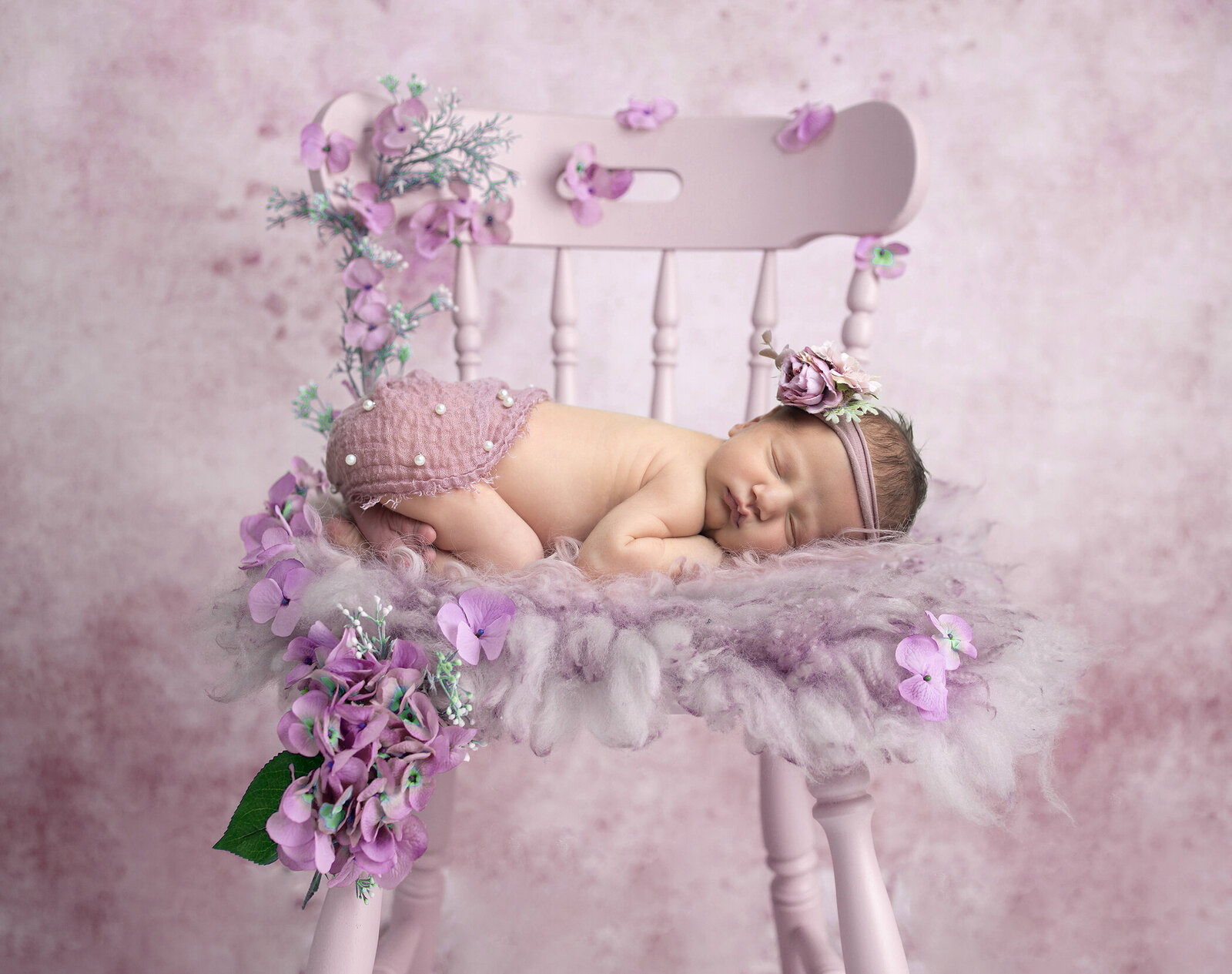 Newborn girl on purple chair, a Dallas newborn photographer.