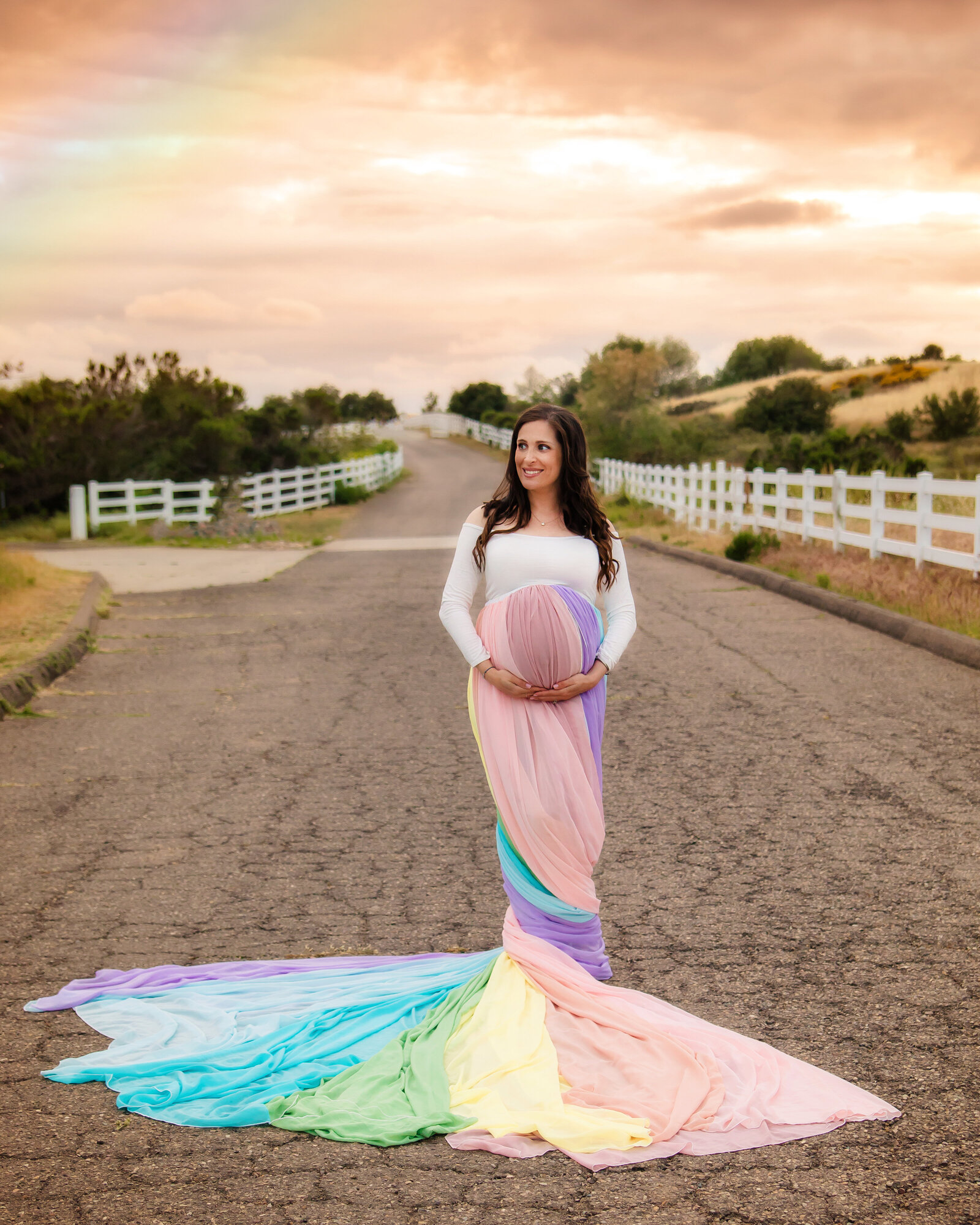 Maternity Photographer, a woman stands on a resdential road, she is pregnant,  she wears a colorful gown