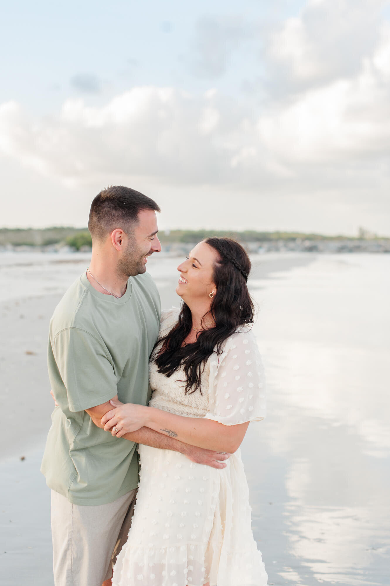 Couple holding each other and smiling during their photography session on the beach