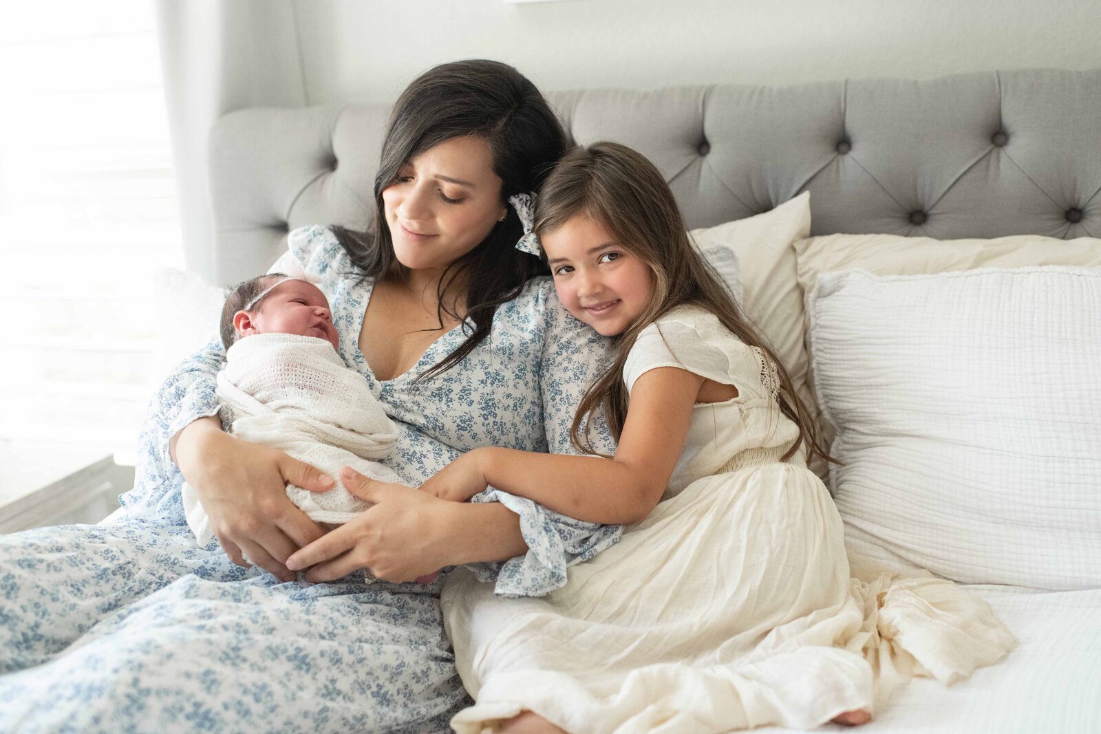 Parents and siblings cuddle on the couch with their newborn in a warm, relaxed setting. A lifestyle newborn session by Moments in Light Photography.