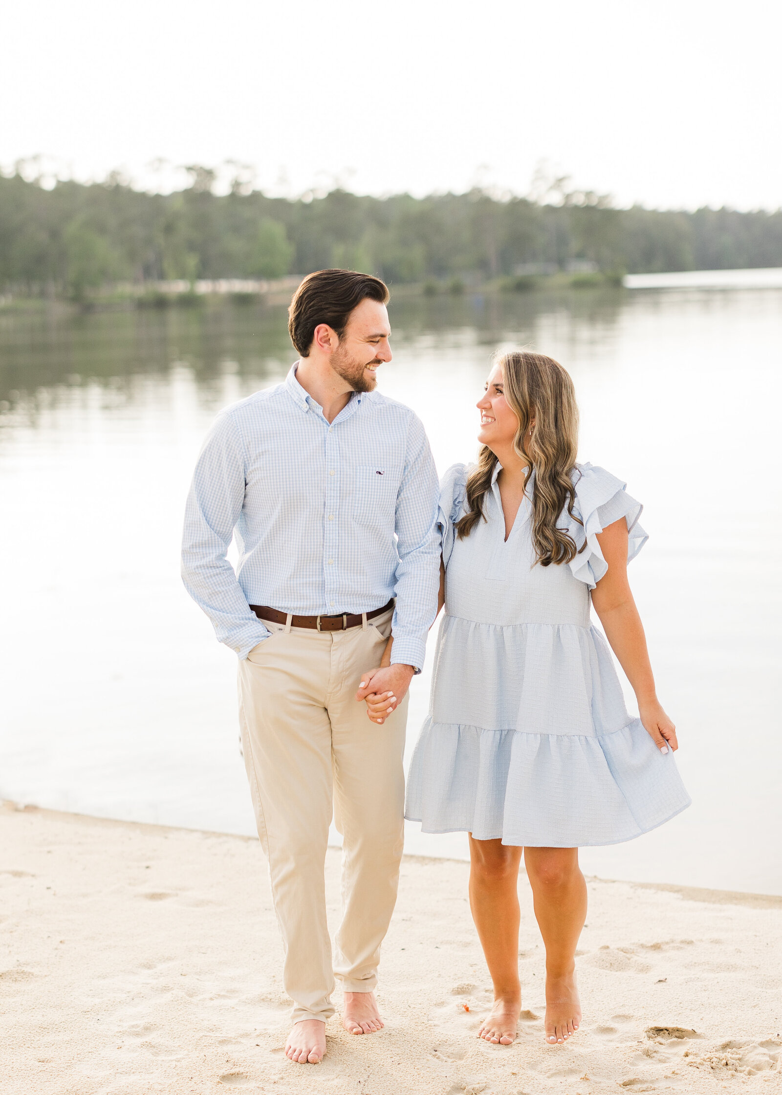 Beachside engagement session of Julianna and Josh holding hands barefoot, captured by Abby Bell Photography in Alabama.