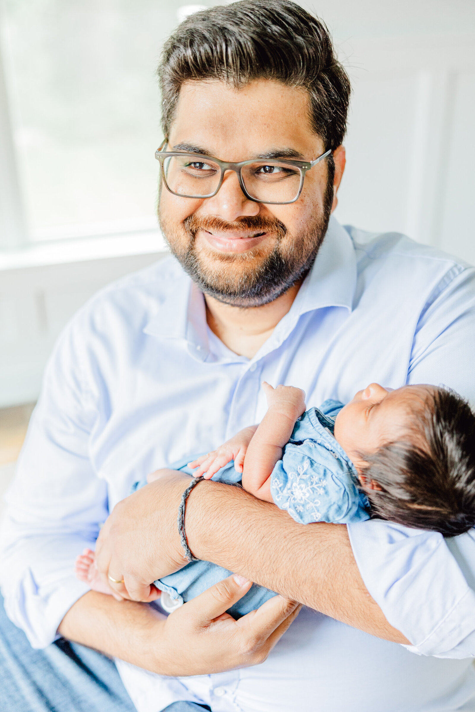 Dad smiling while holding his newborn daughter