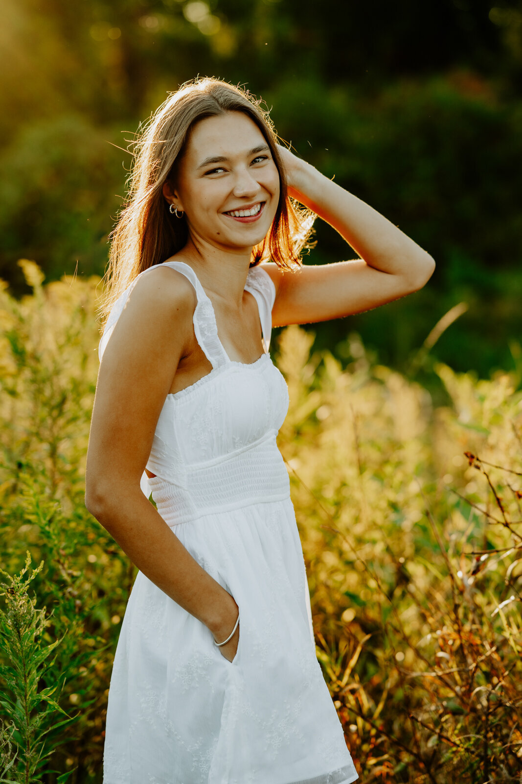 Girl wearing a white dress with yellow flowers behind her. 