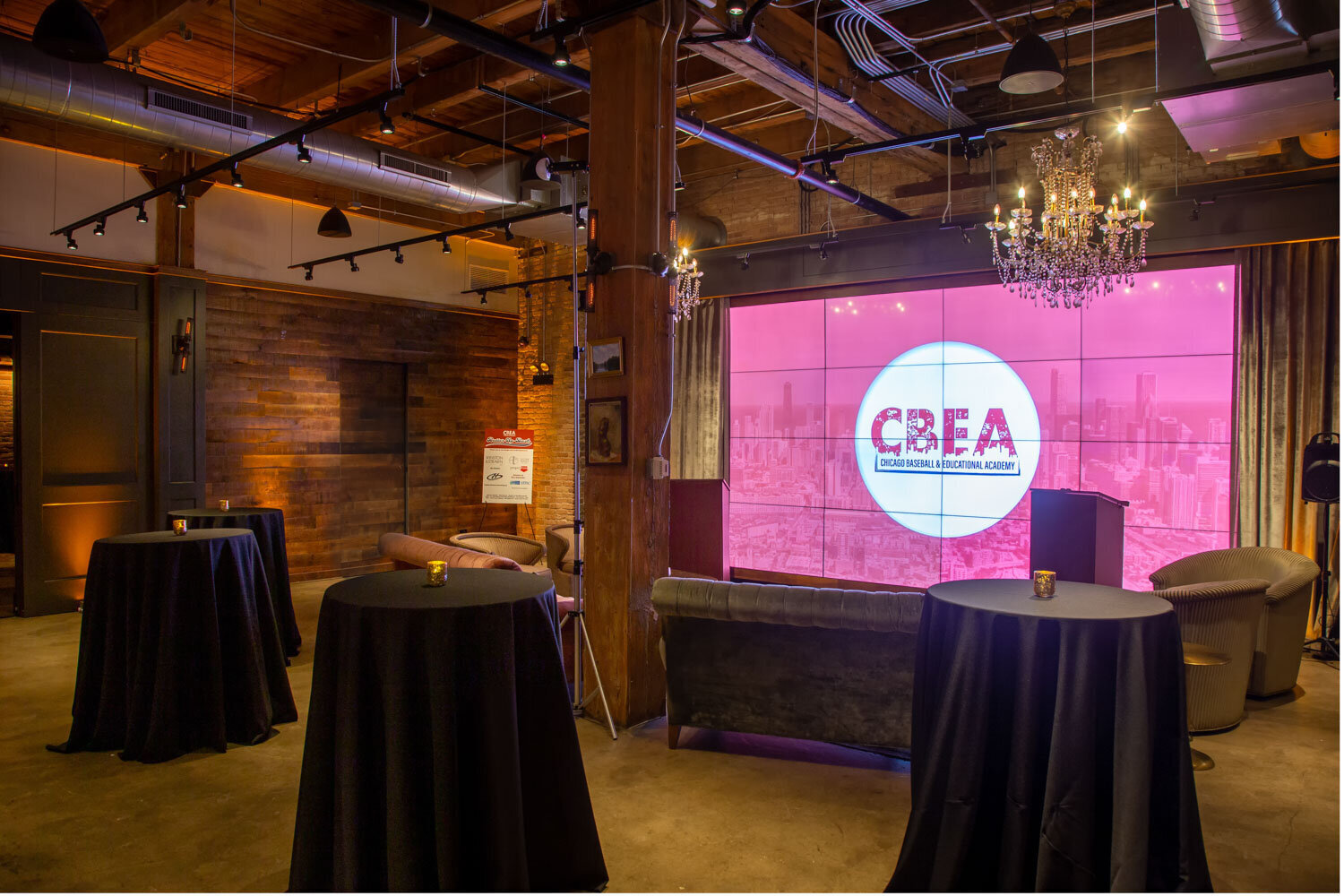 Event venue with cocktail tables and CREA logo displayed on a screen