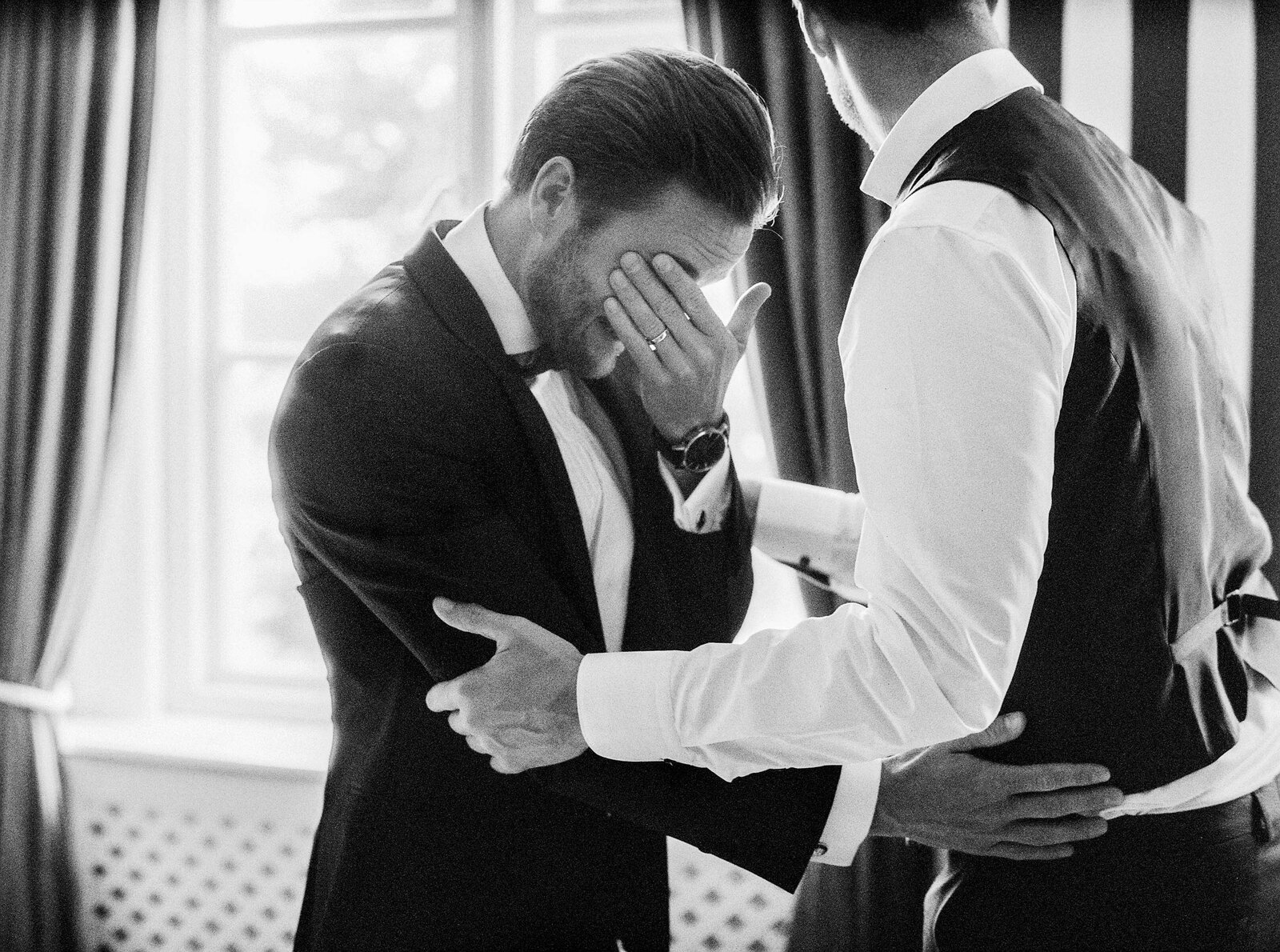 Groom wiping away tears photographed on black and white film