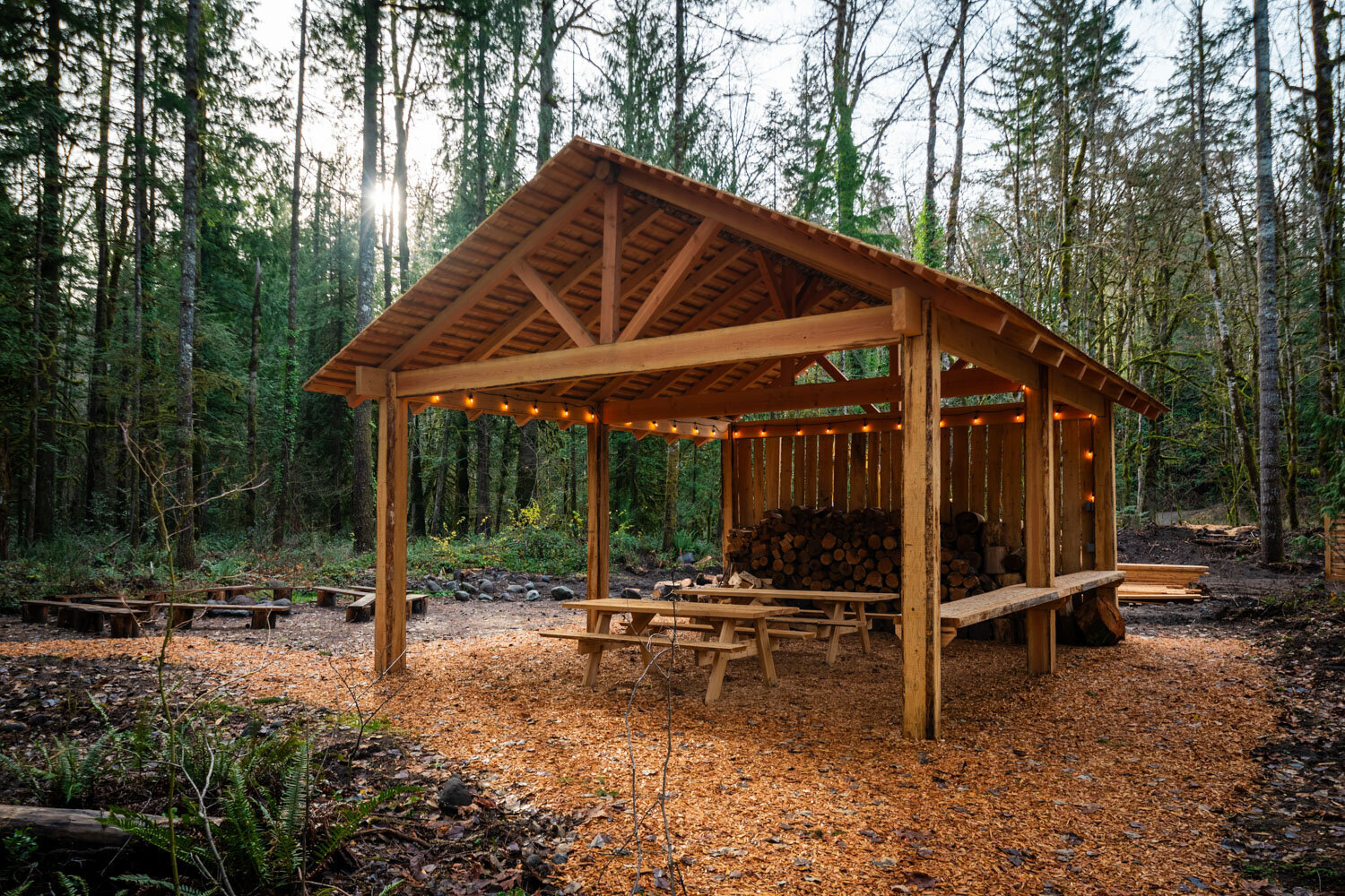 Open wooden pavilion with picnic tables and string lights