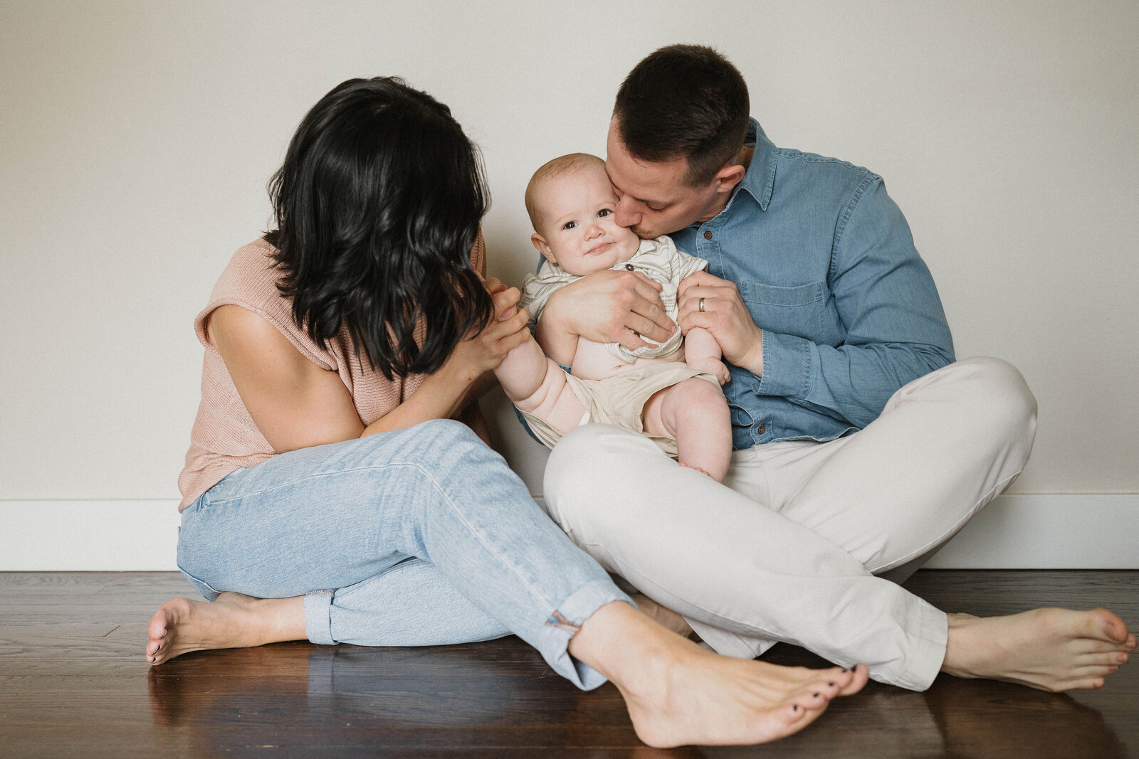 mom and dad kissing chunky baby