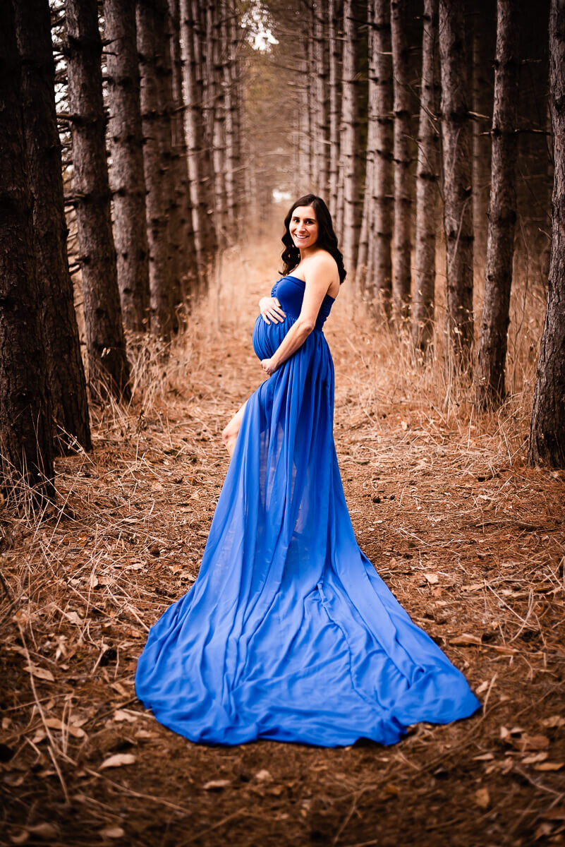 Mother shows off long train of Toronto Maternity Photographer's blue gown
