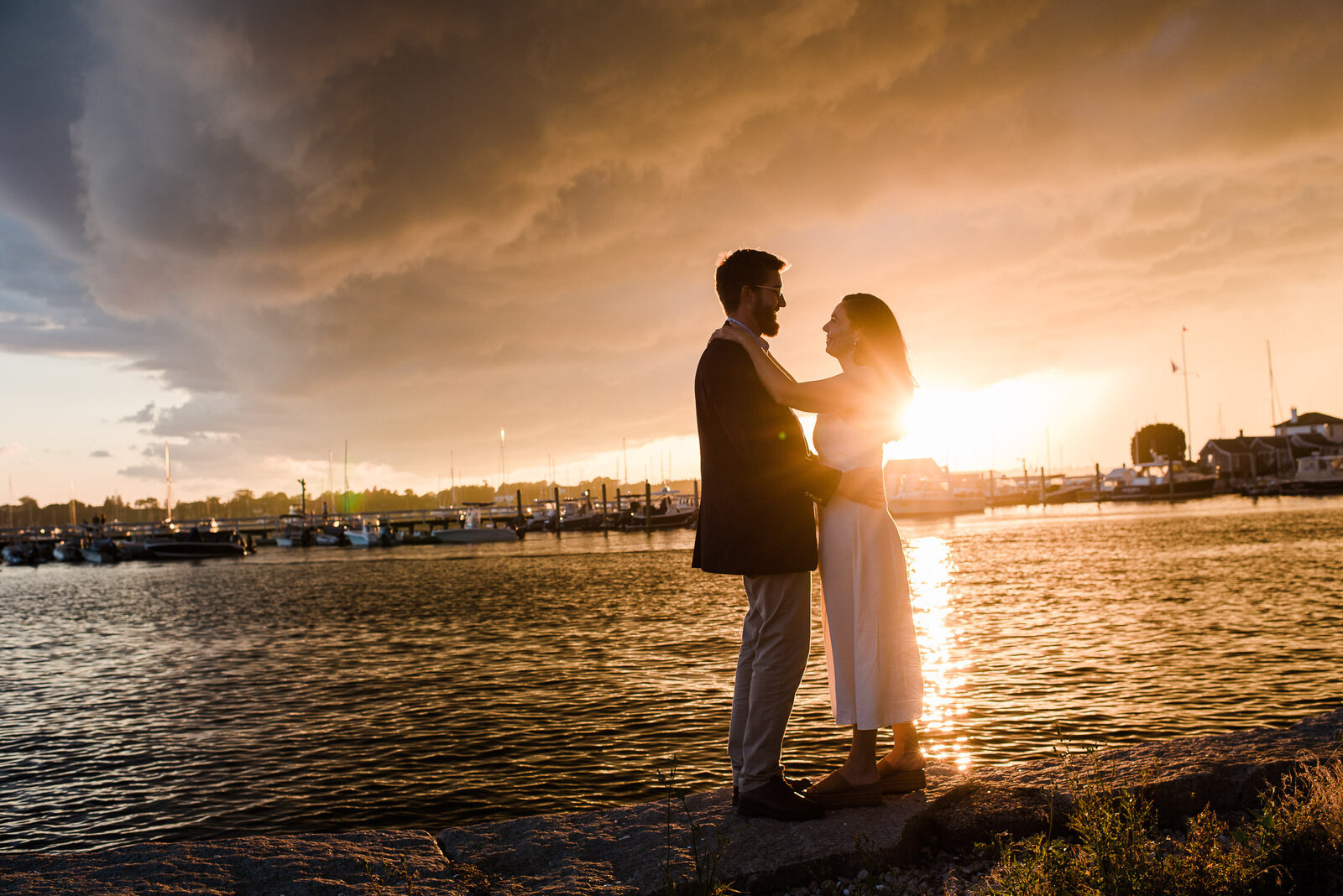couple face each other at sunset by water