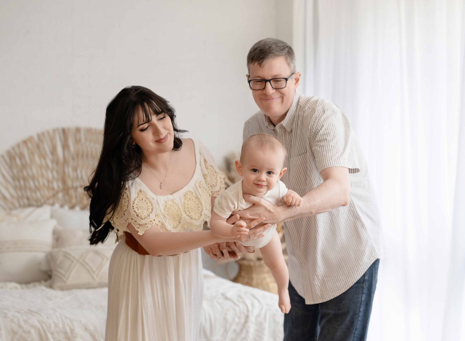 Boho lifestyle bedroom with mom and dad swing baby in the air.