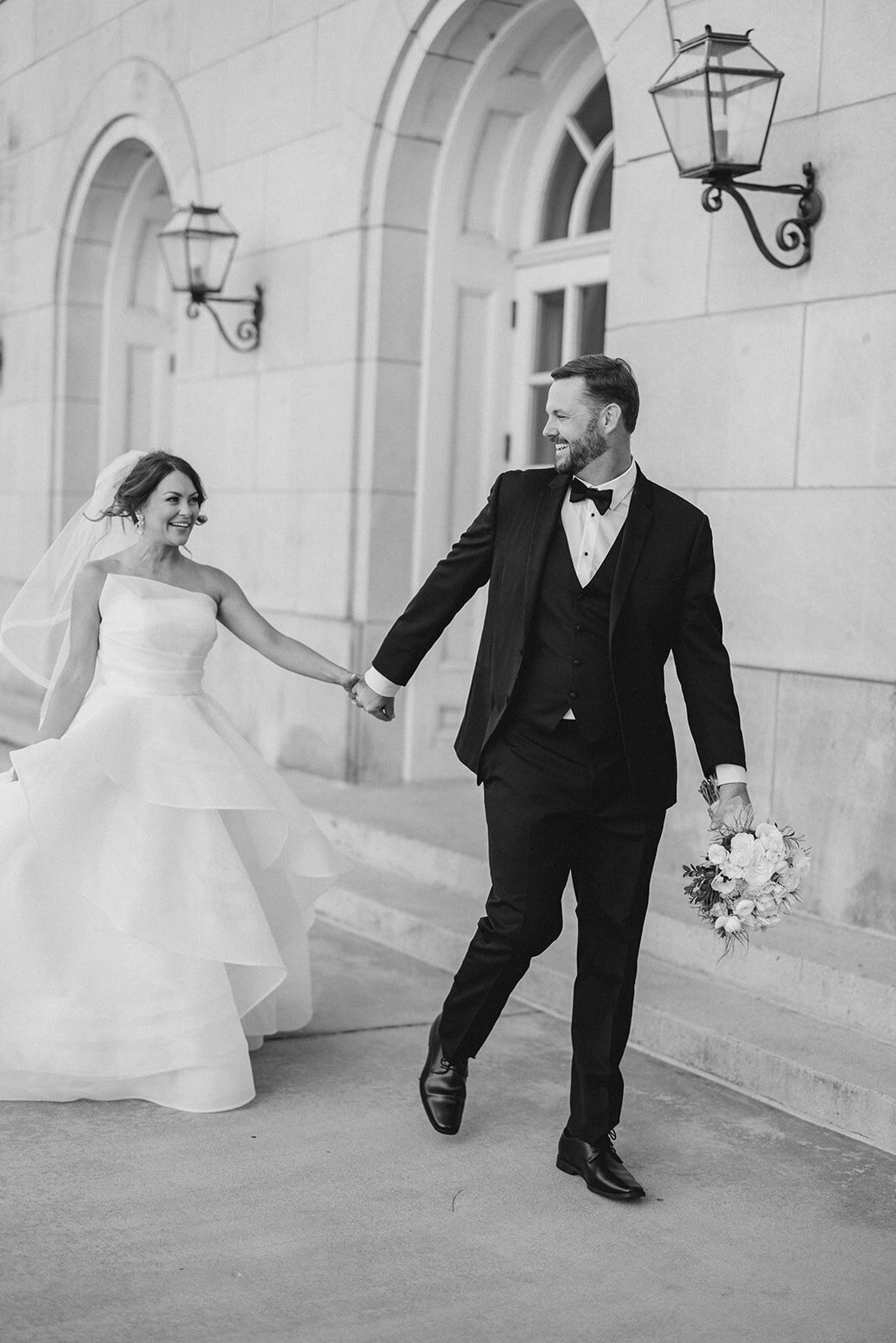 Bride runs with groom in front of European style wedding venue in Georgia