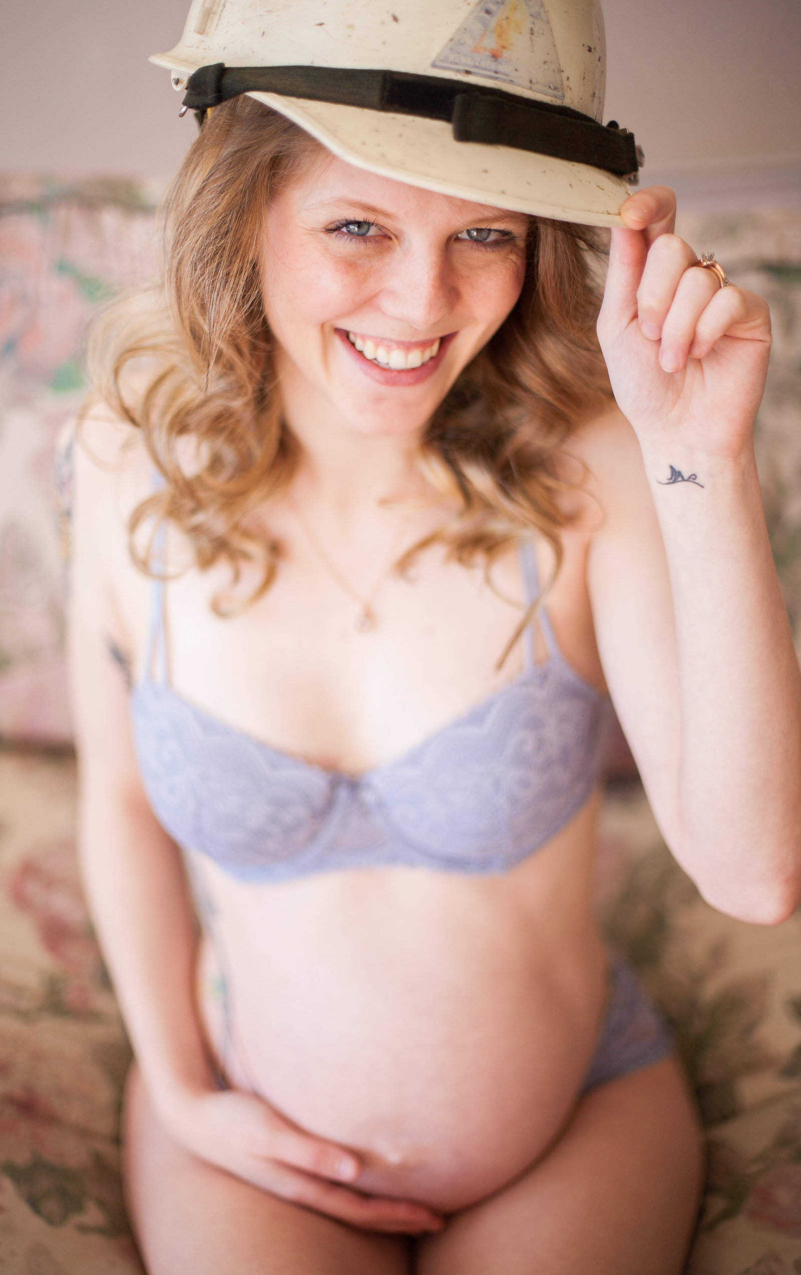 A blonde woman with a pregnant belly in heather grey lingerie.