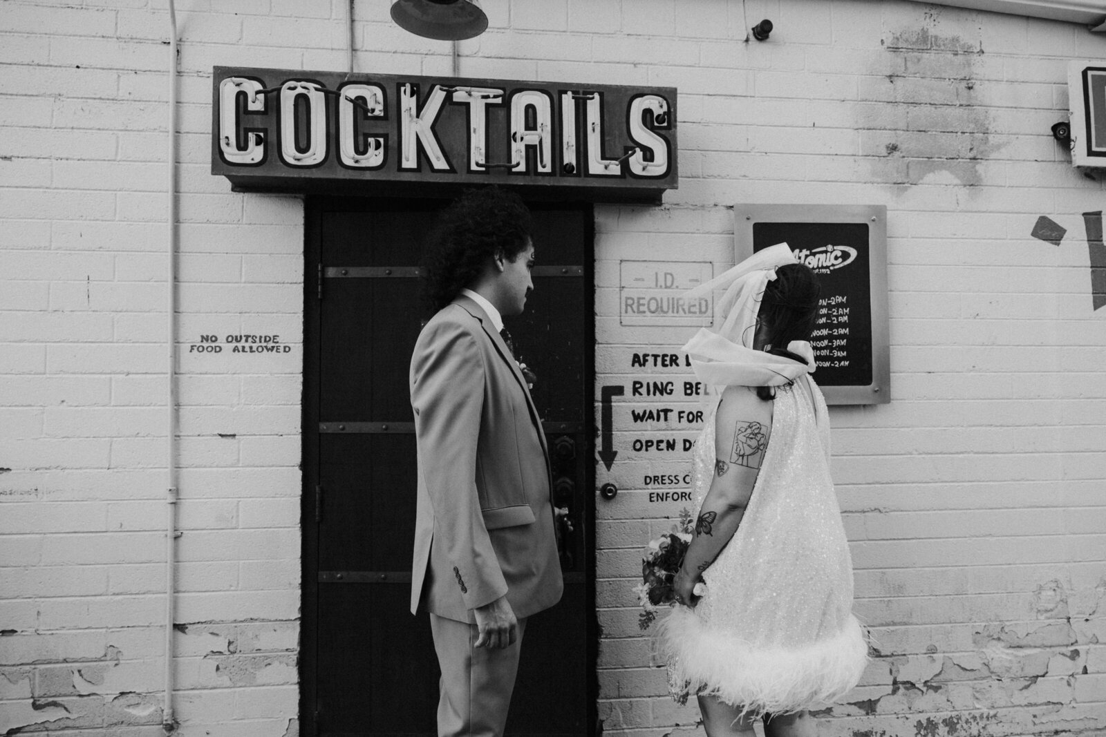A couple stands outside of a bar on their elopement day.