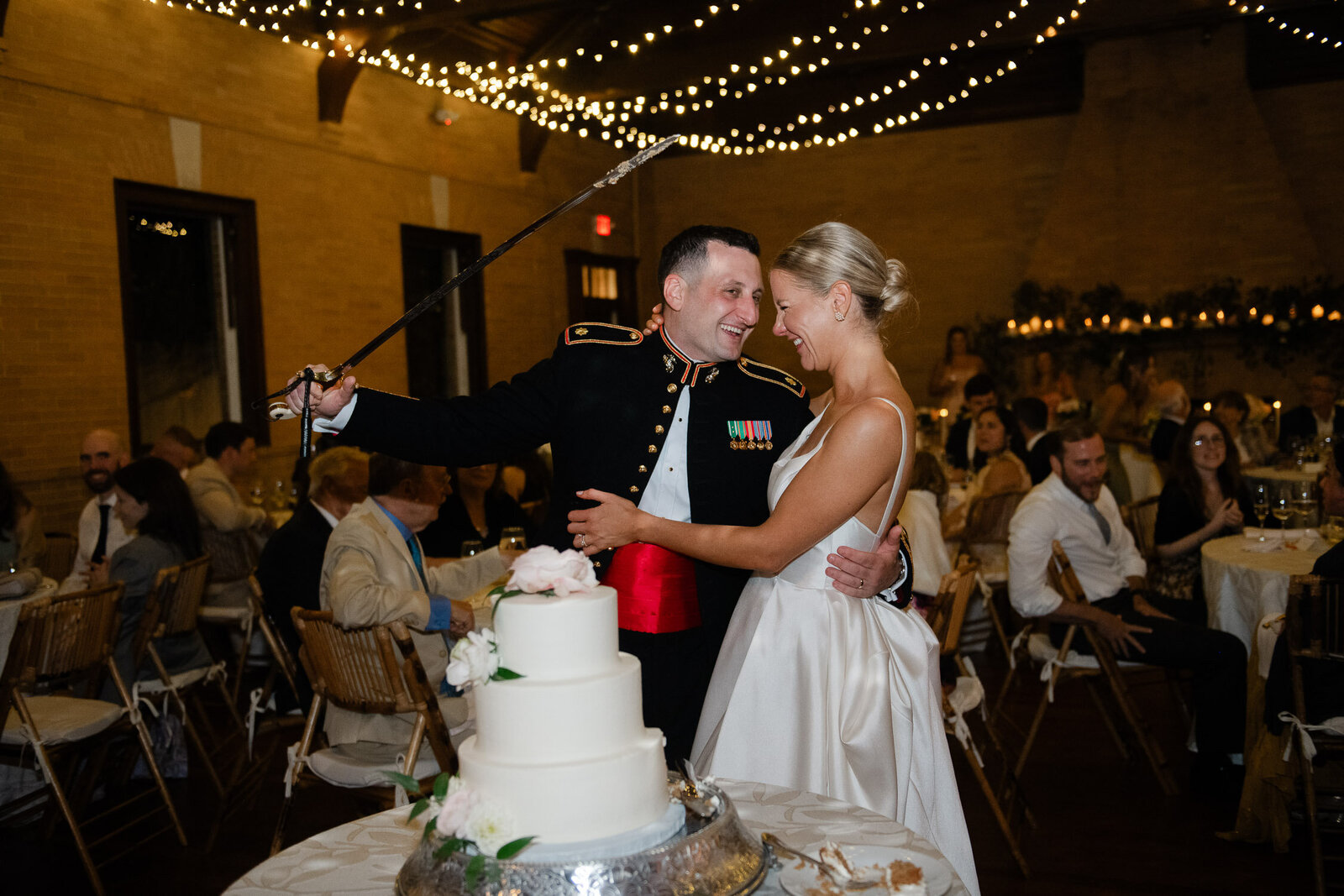 groom playfully uses military sword for cake cutting
