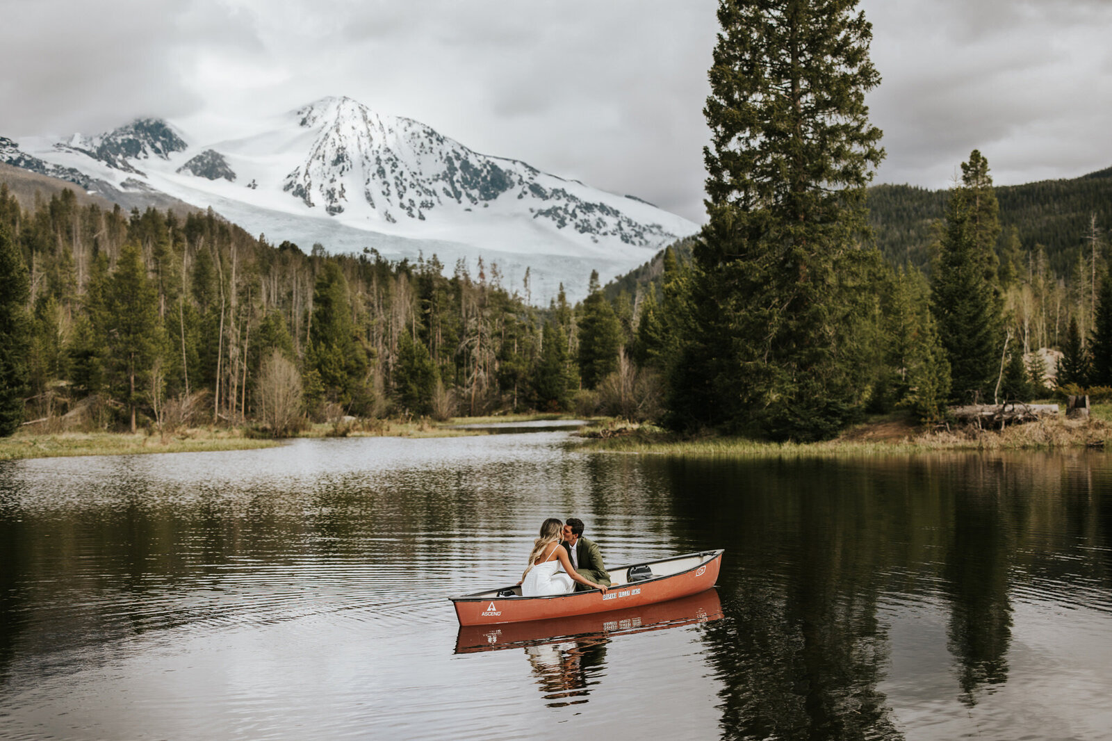 Couple canoe-ing on a lake on their elopement day in the mountains.