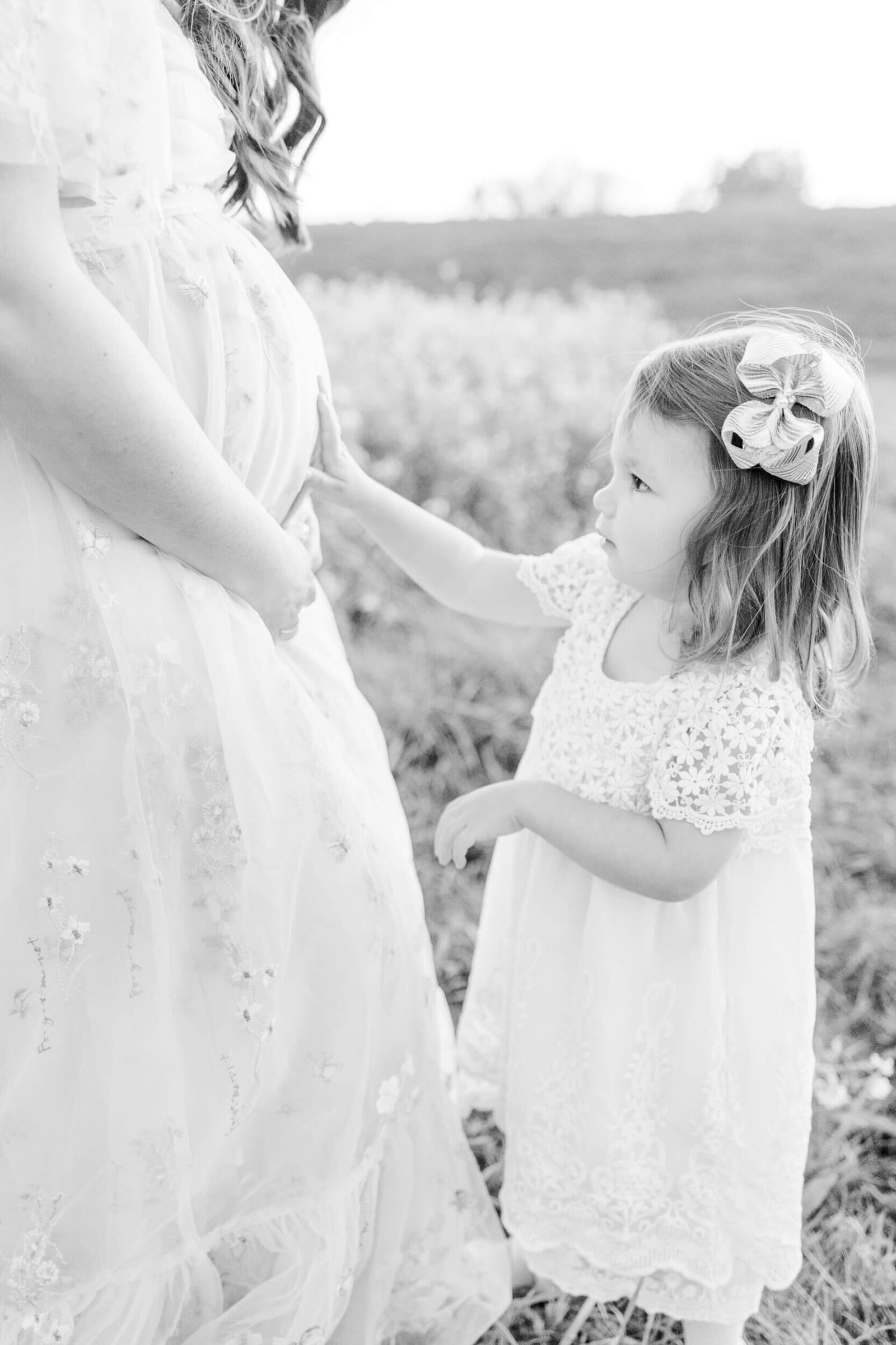 Little girl reaches for her pregnant mom's baby bump