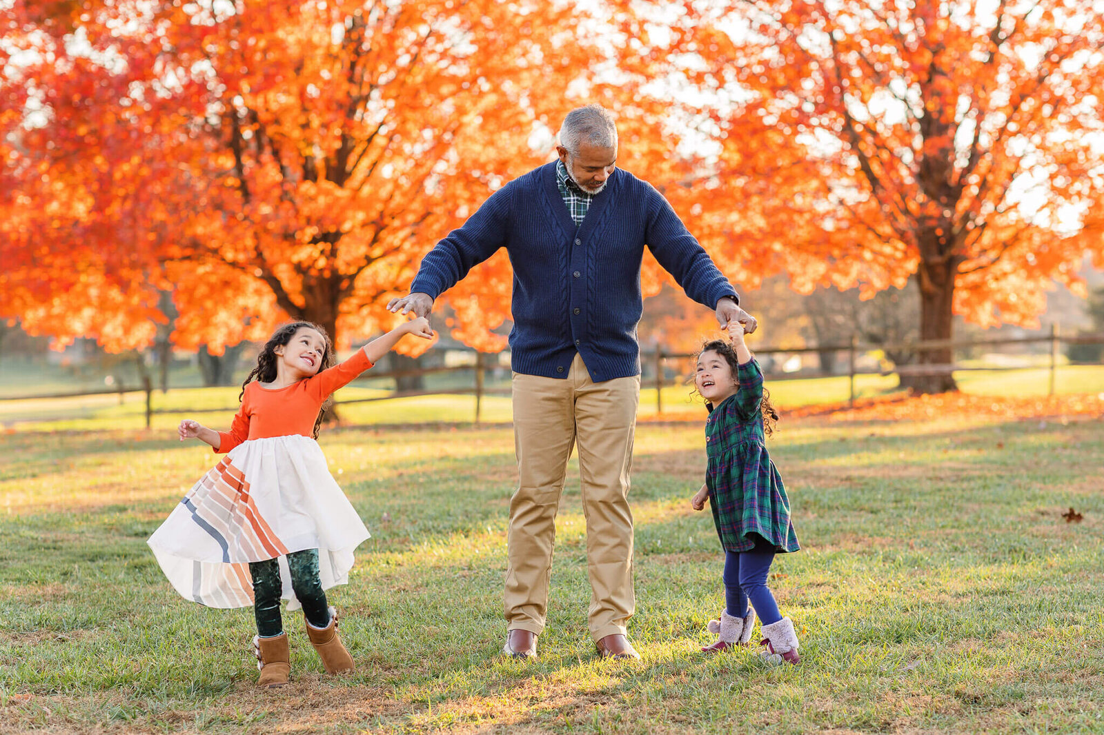 A dad and his daughters dancing at a Northern Virginia park