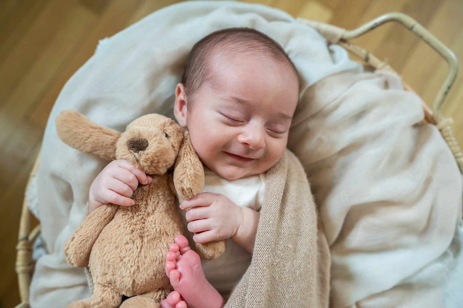baby holding a stuffed dog in a basket wrap