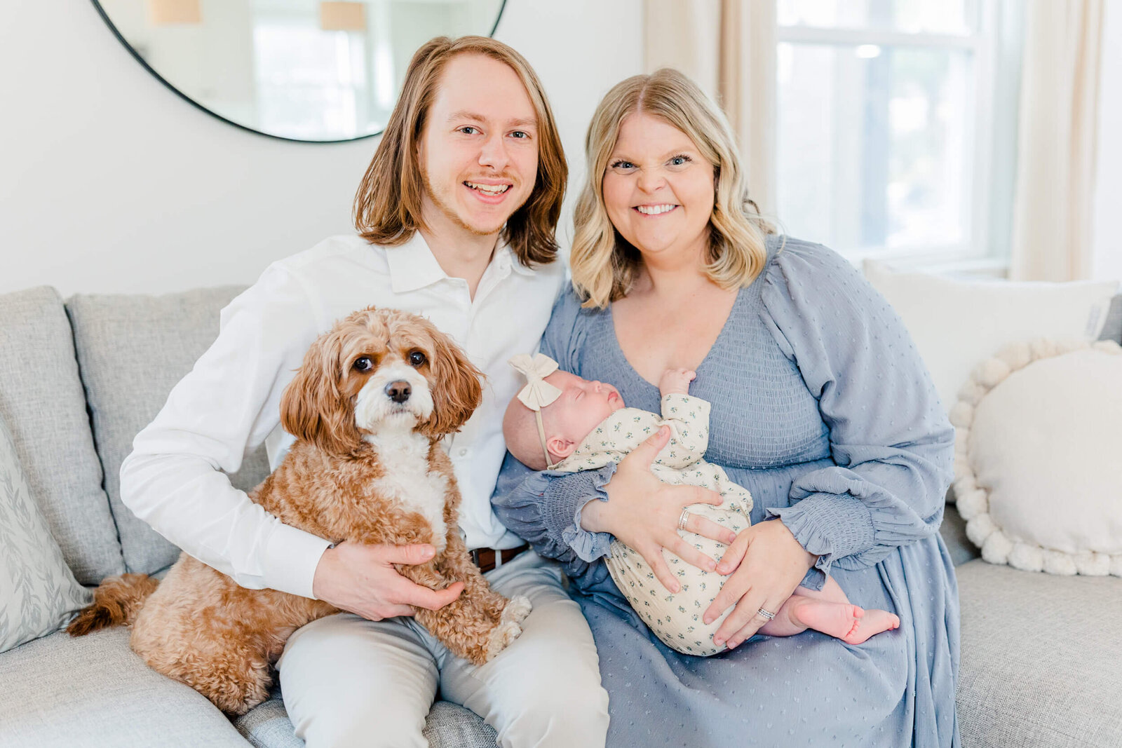 Mom and dad smile with their newborn and dog