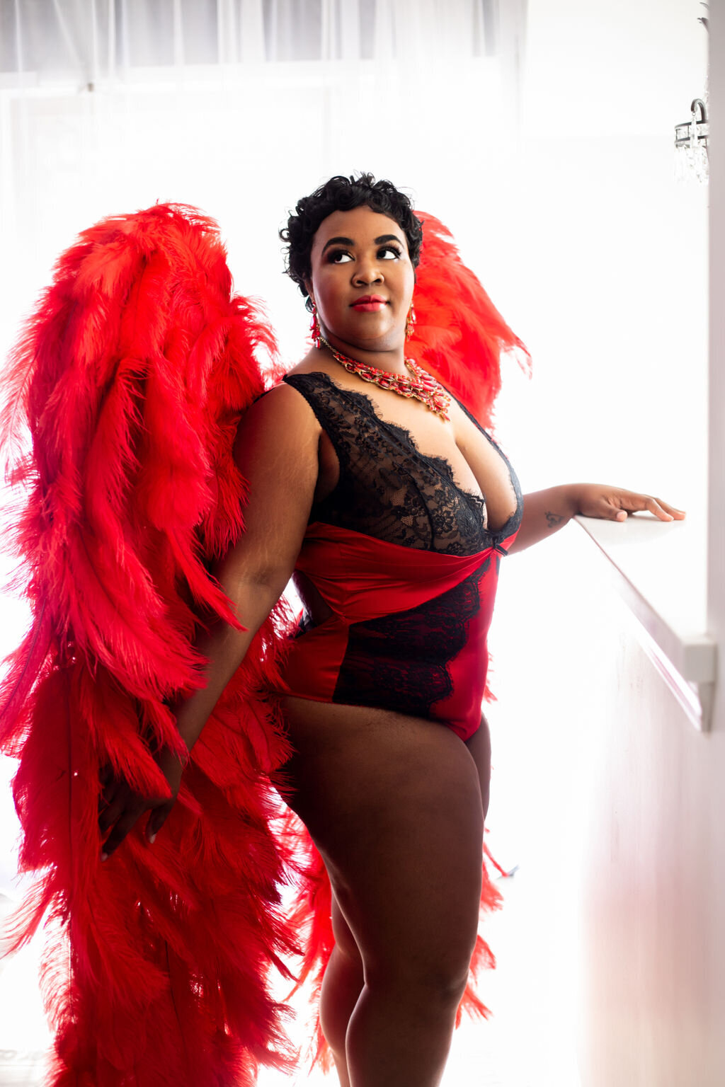 woman posed with red wings in red and black lingerie