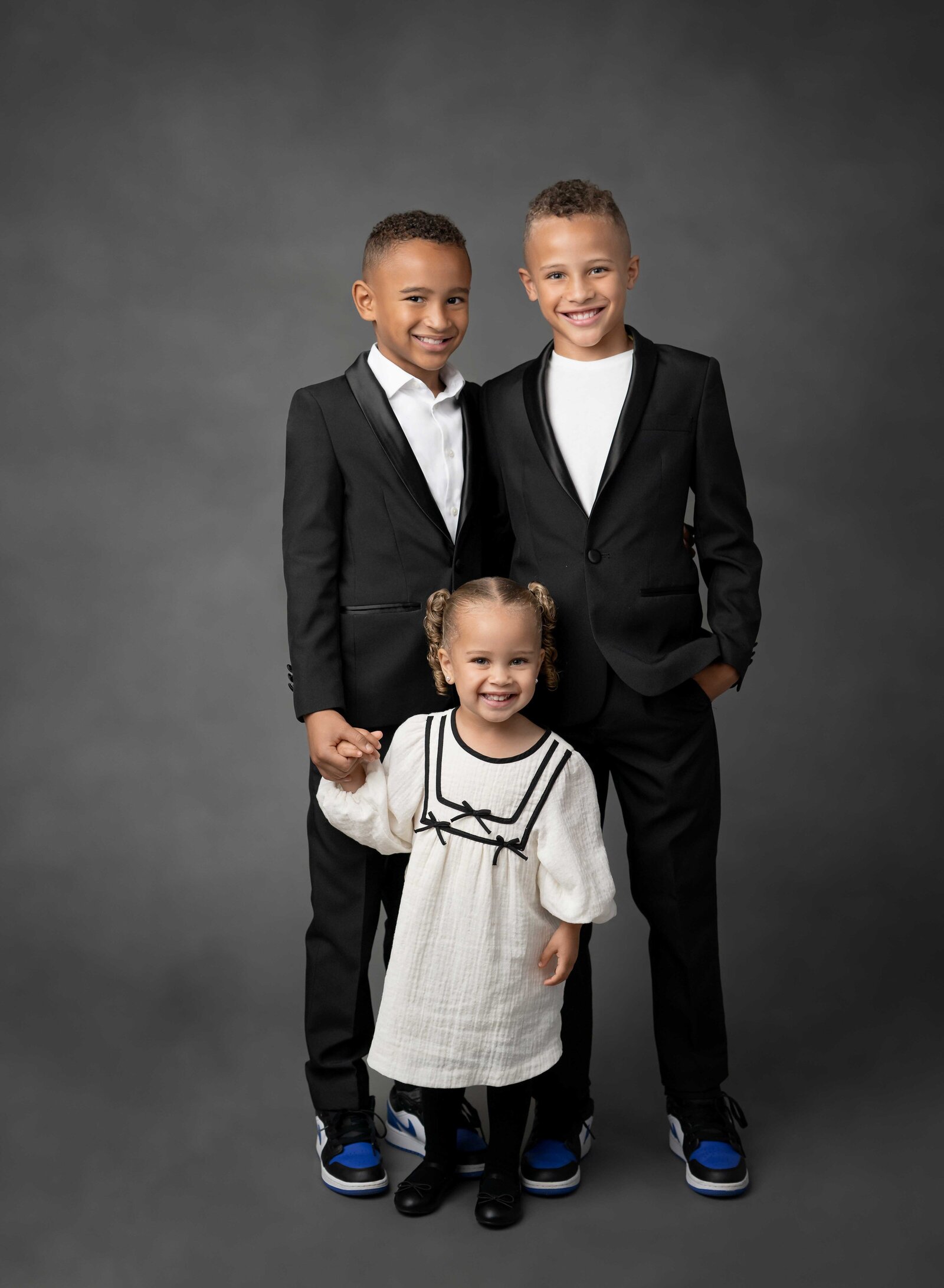 Brothers and sister holding hands for photo. Family photo taken at Atlanta Photo Studio by Jenni Nikki Photography.