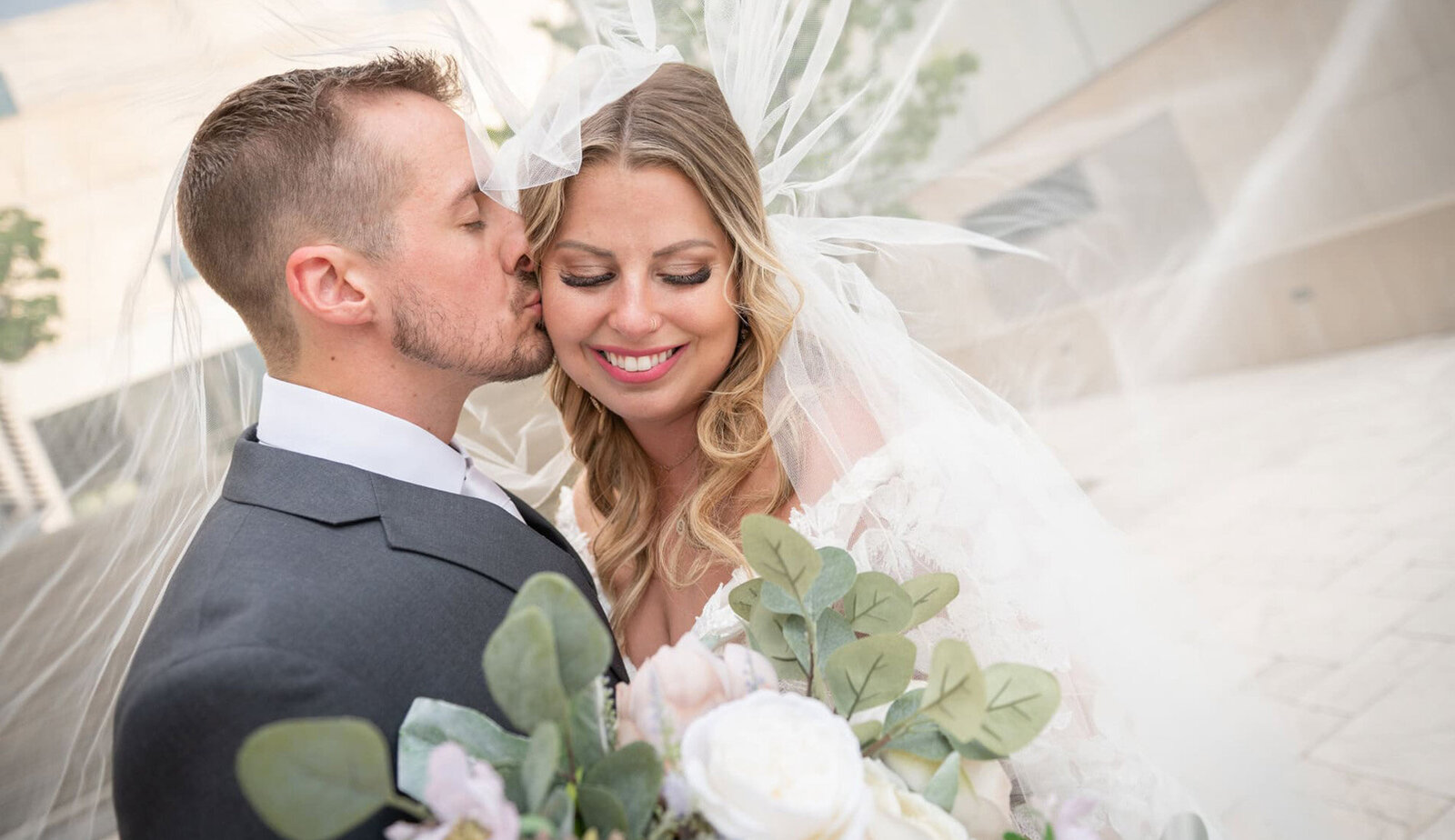 groom kisses bride's cheek under veil