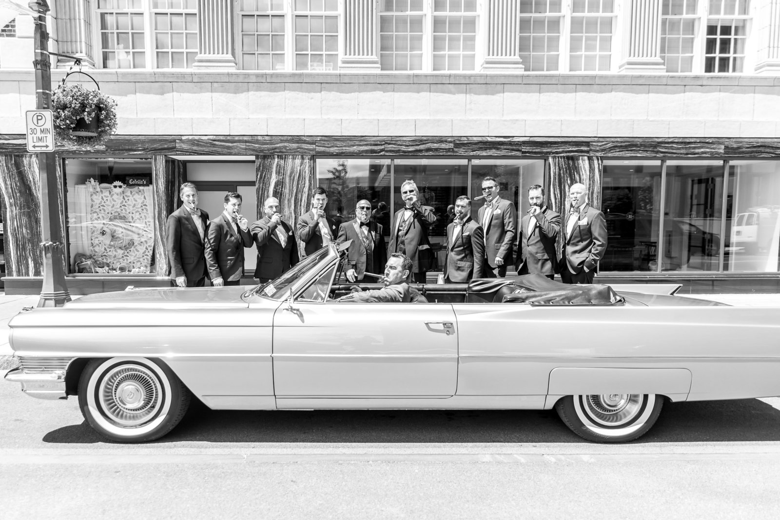 Groomsmen pose for a vintage  car photo in front of the Syracuse Marriott Downtown